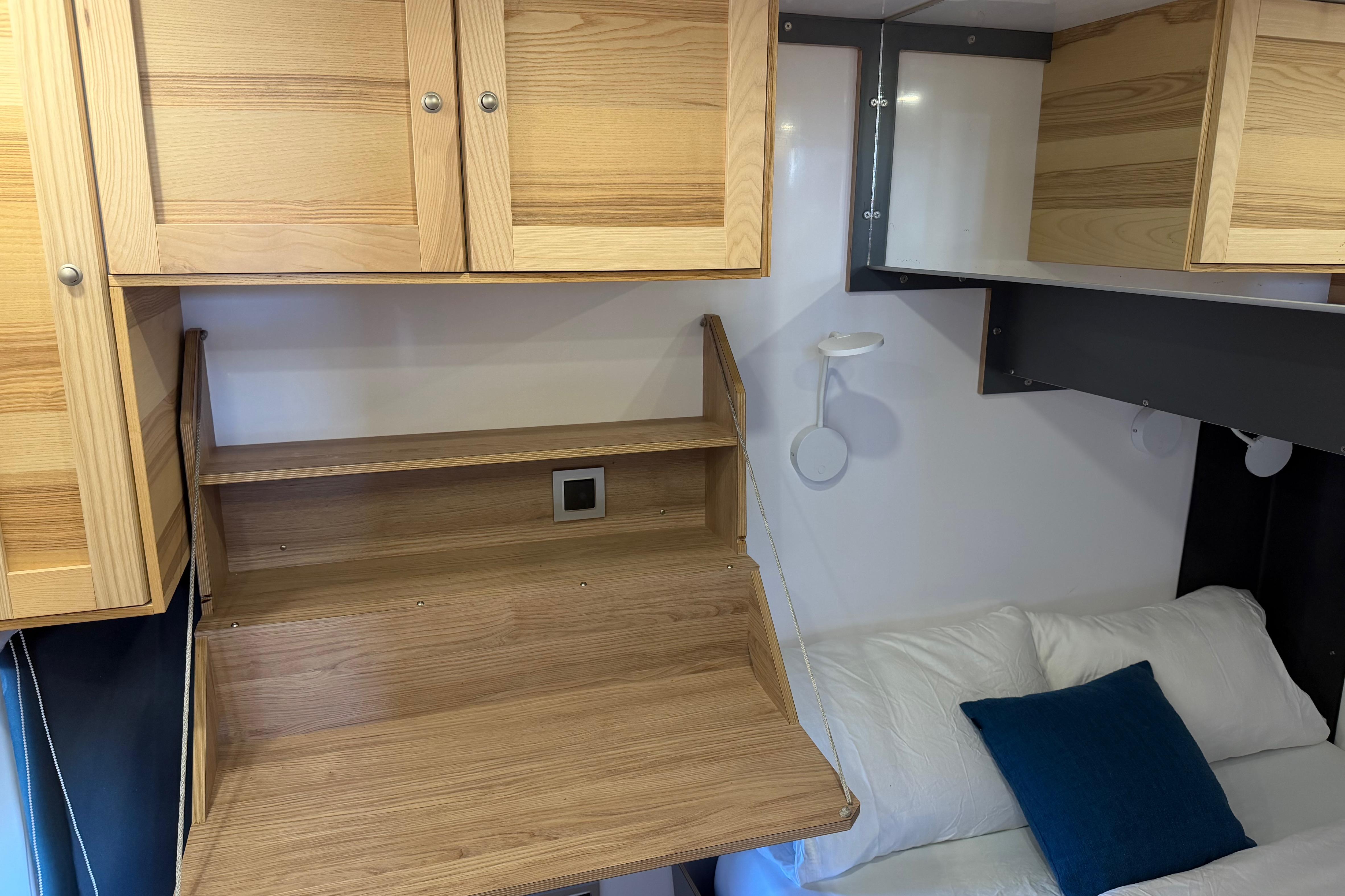 Compact interior of 2022 Navisyo NV.08 with wooden cabinets and foldable desk.