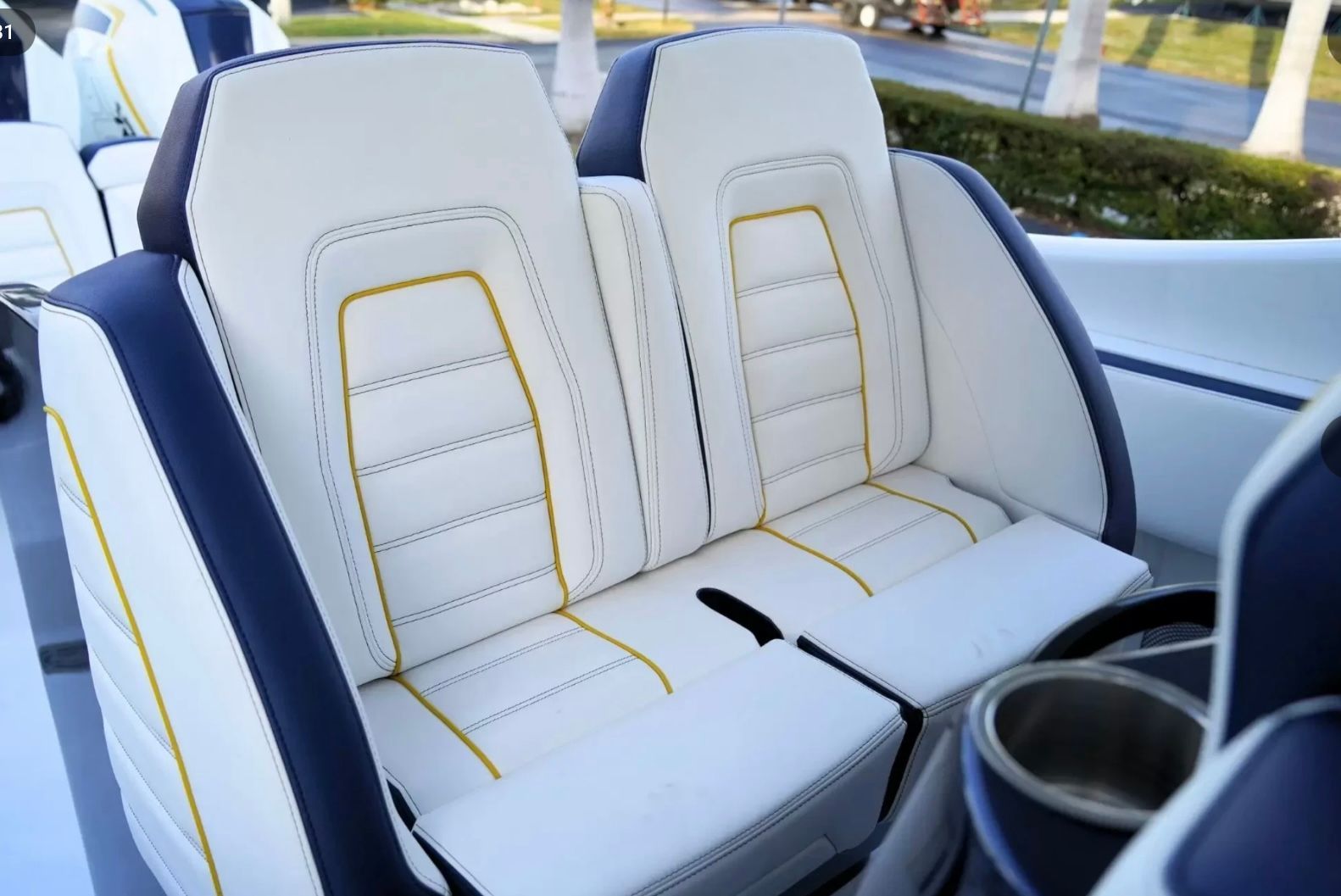 Two luxurious white seats with yellow stitching on a boat.