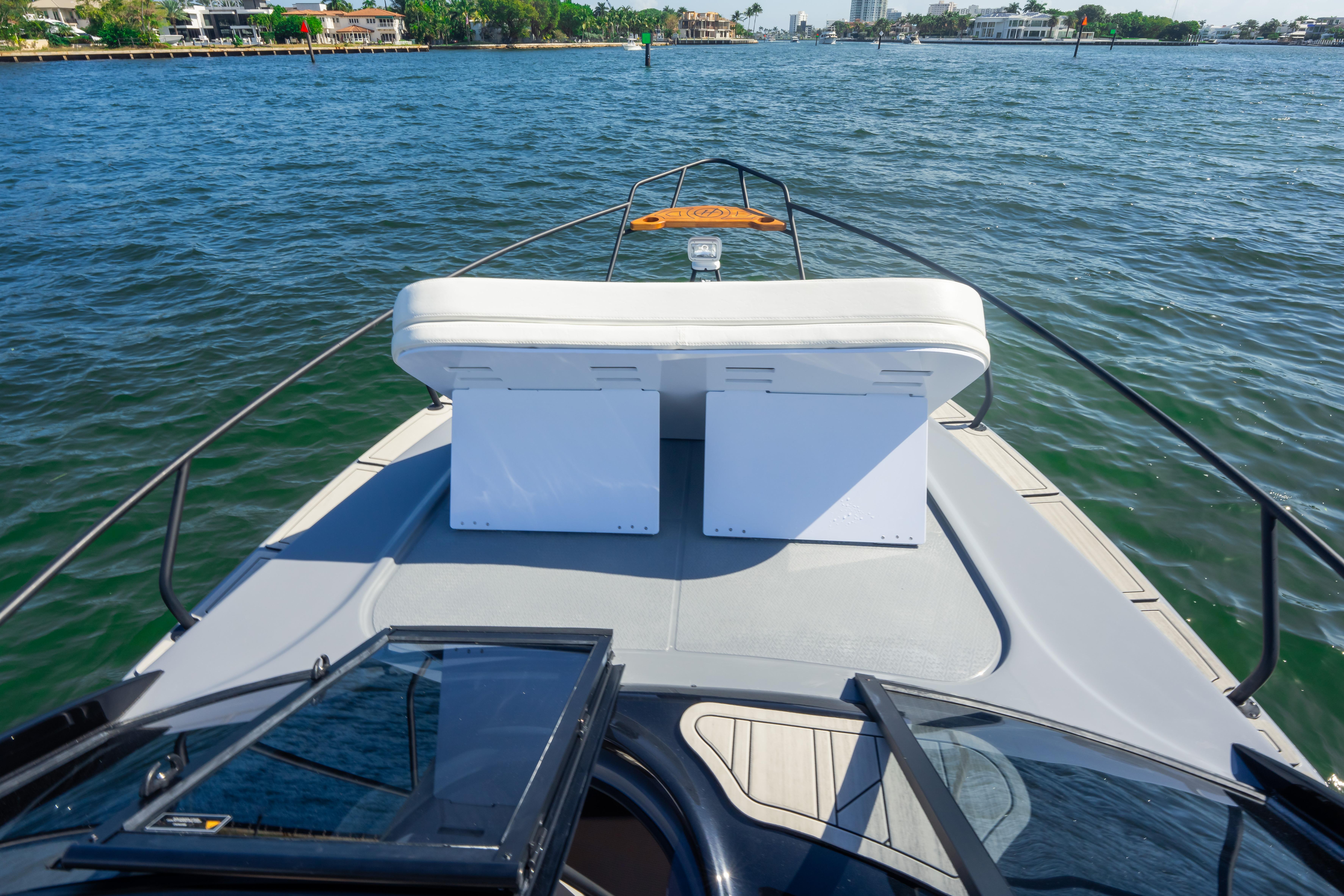 Front deck view of 2026 Hanover 305 boat on water, featuring seating and open hatch.
