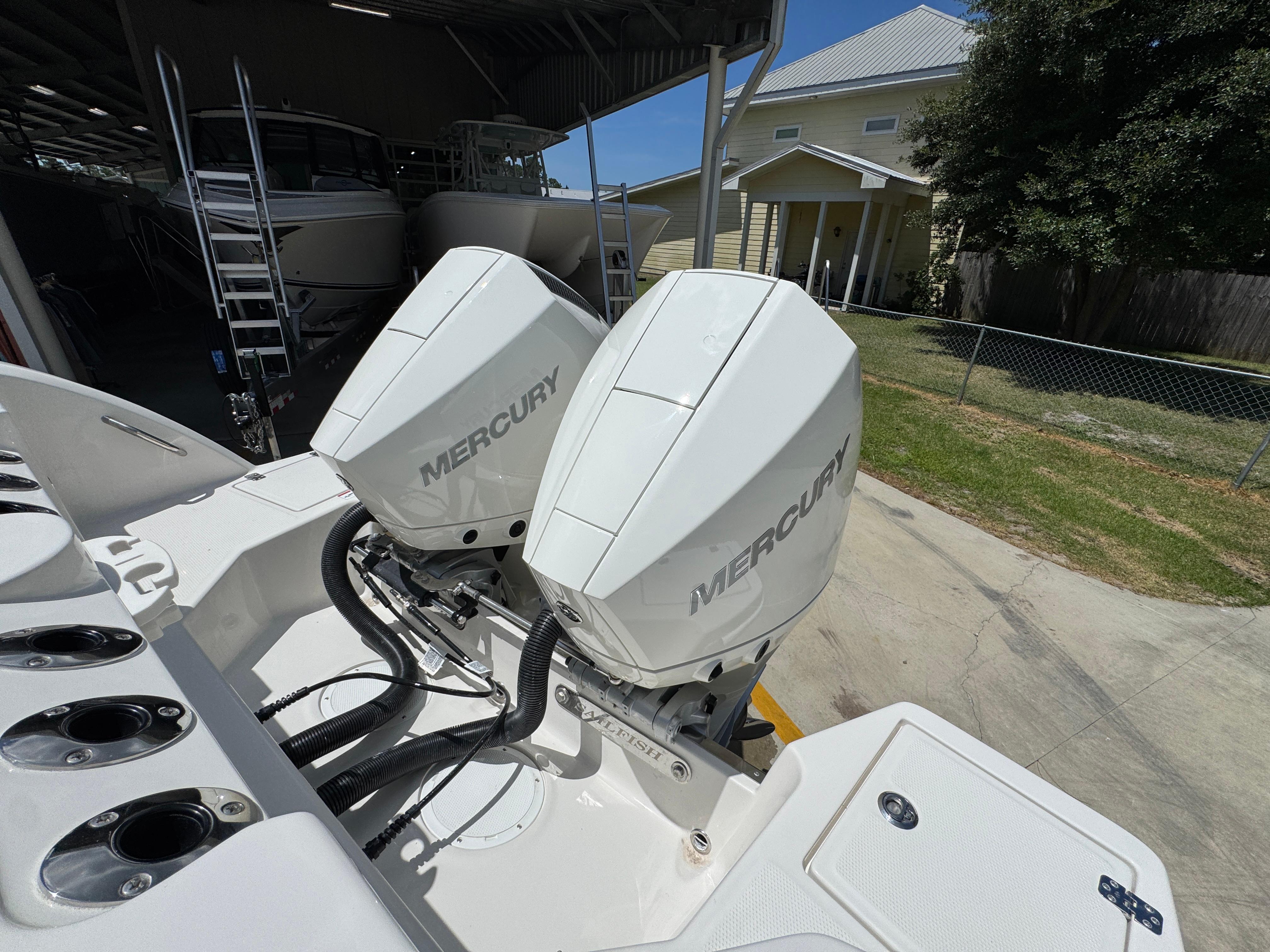 Twin Mercury outboard engines on a 2026 Sailfish 272 CC boat, parked outdoors.