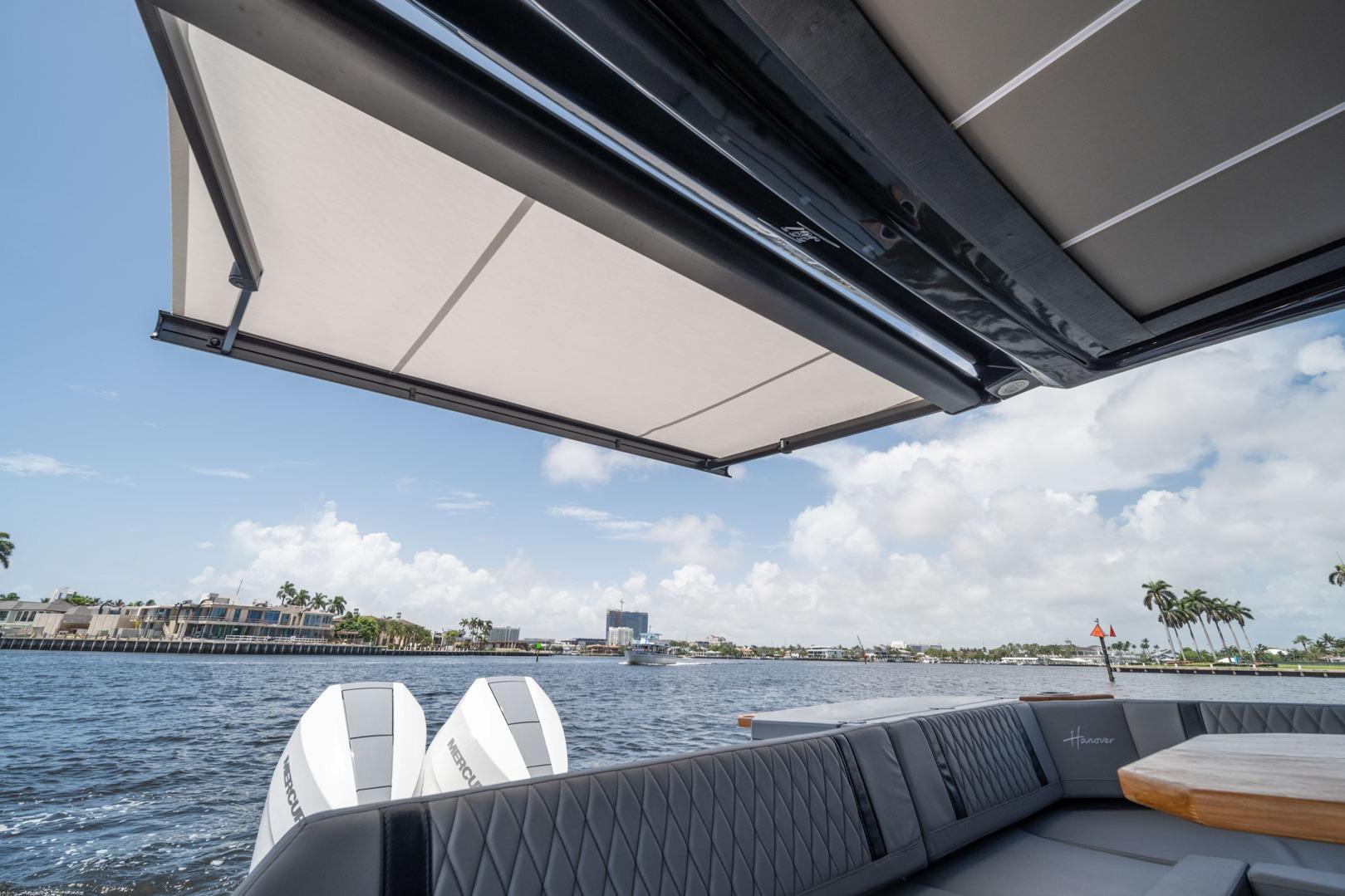 2026 Hanover 387 boat with awning, luxurious seating, and scenic waterfront view.