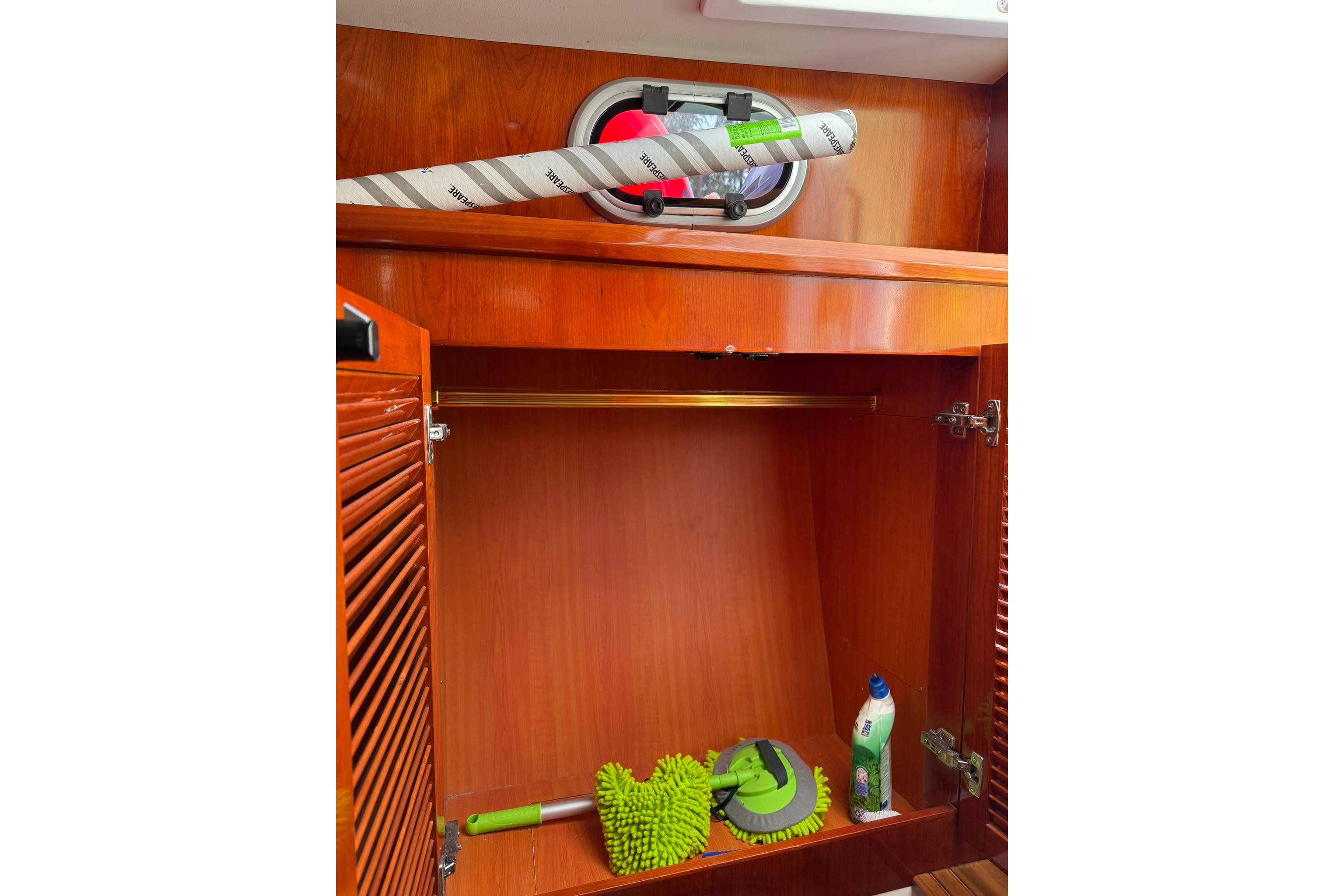 Wooden cabinet interior on a 2020 SeaPiper 35 boat, with cleaning supplies.