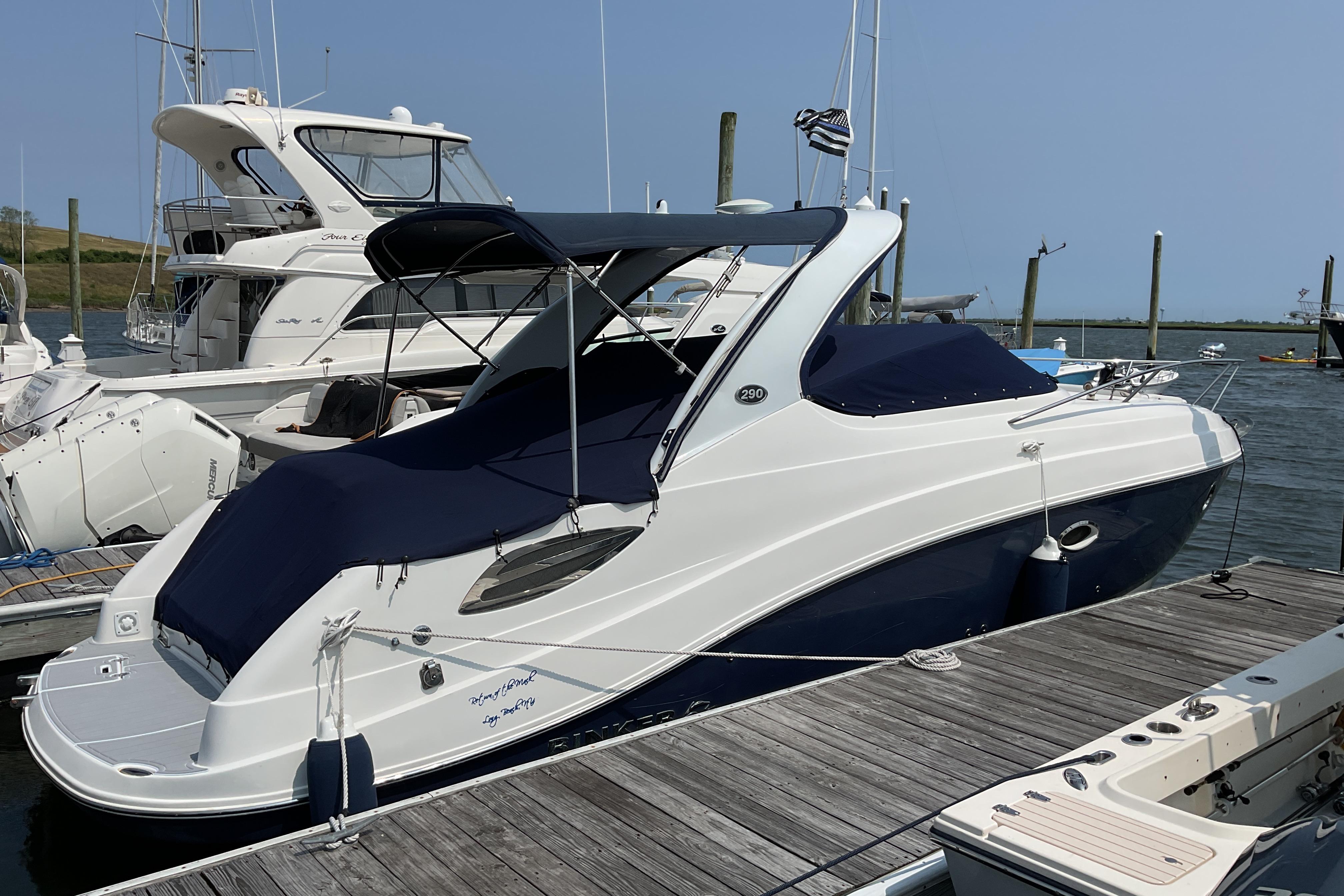 2013 Rinker 290 Express Cruiser docked at marina, covered with navy blue canvas.
