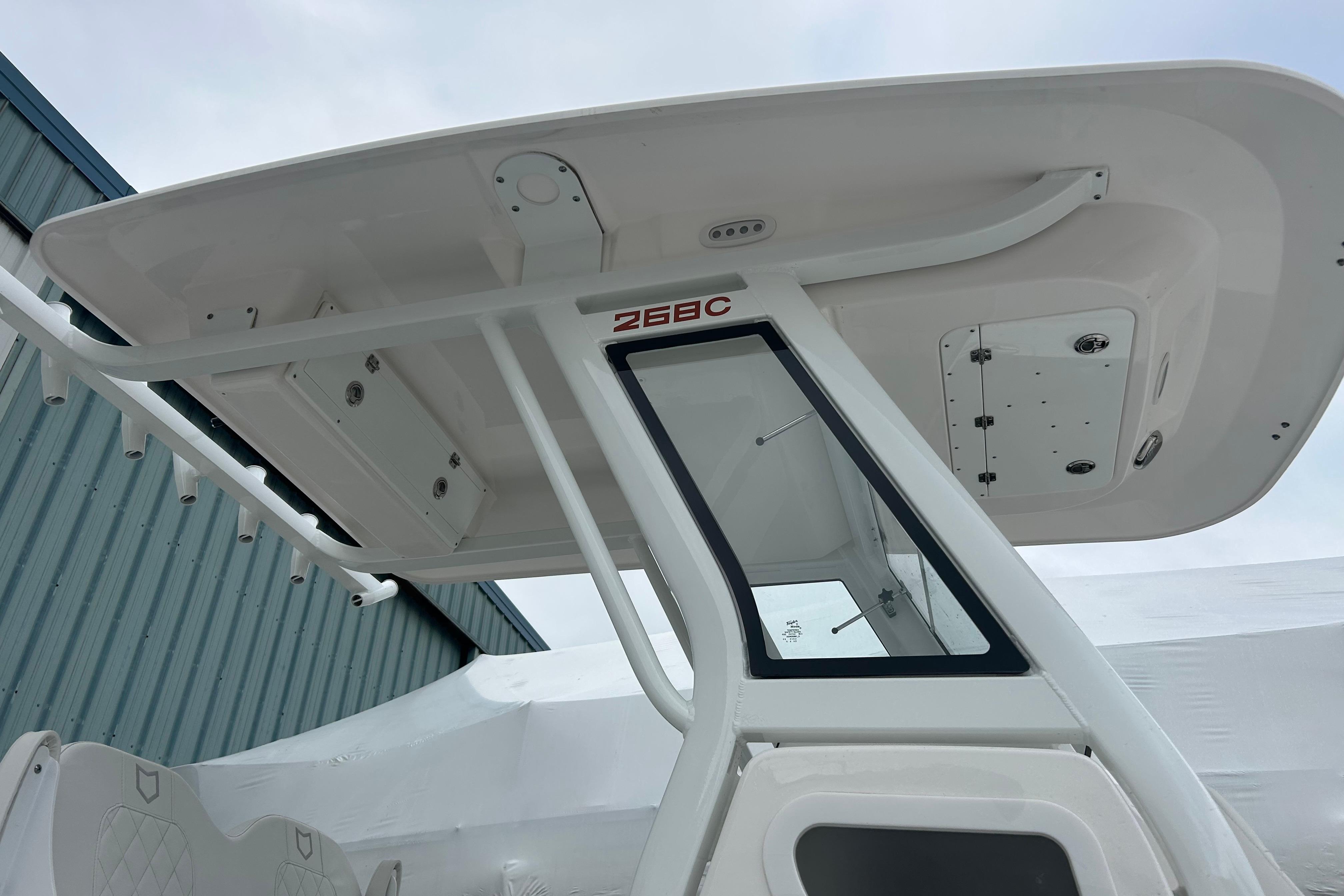 2026 Sea Fox 268 Commander boat with T-top and console, docked near a building.