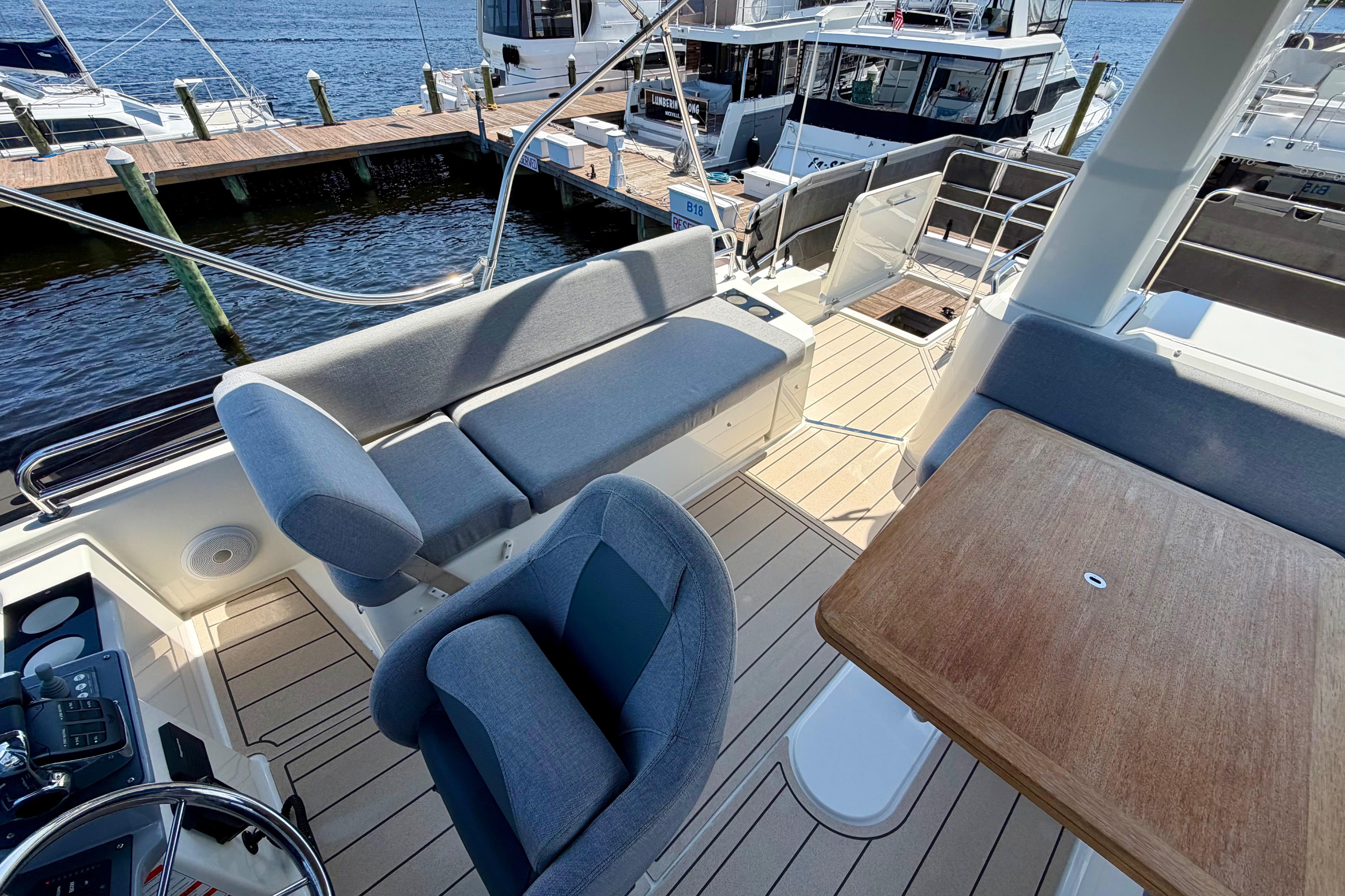 Flybridge of 2025 Beneteau Swift Trawler 41 Fly with seating and table, docked at marina.