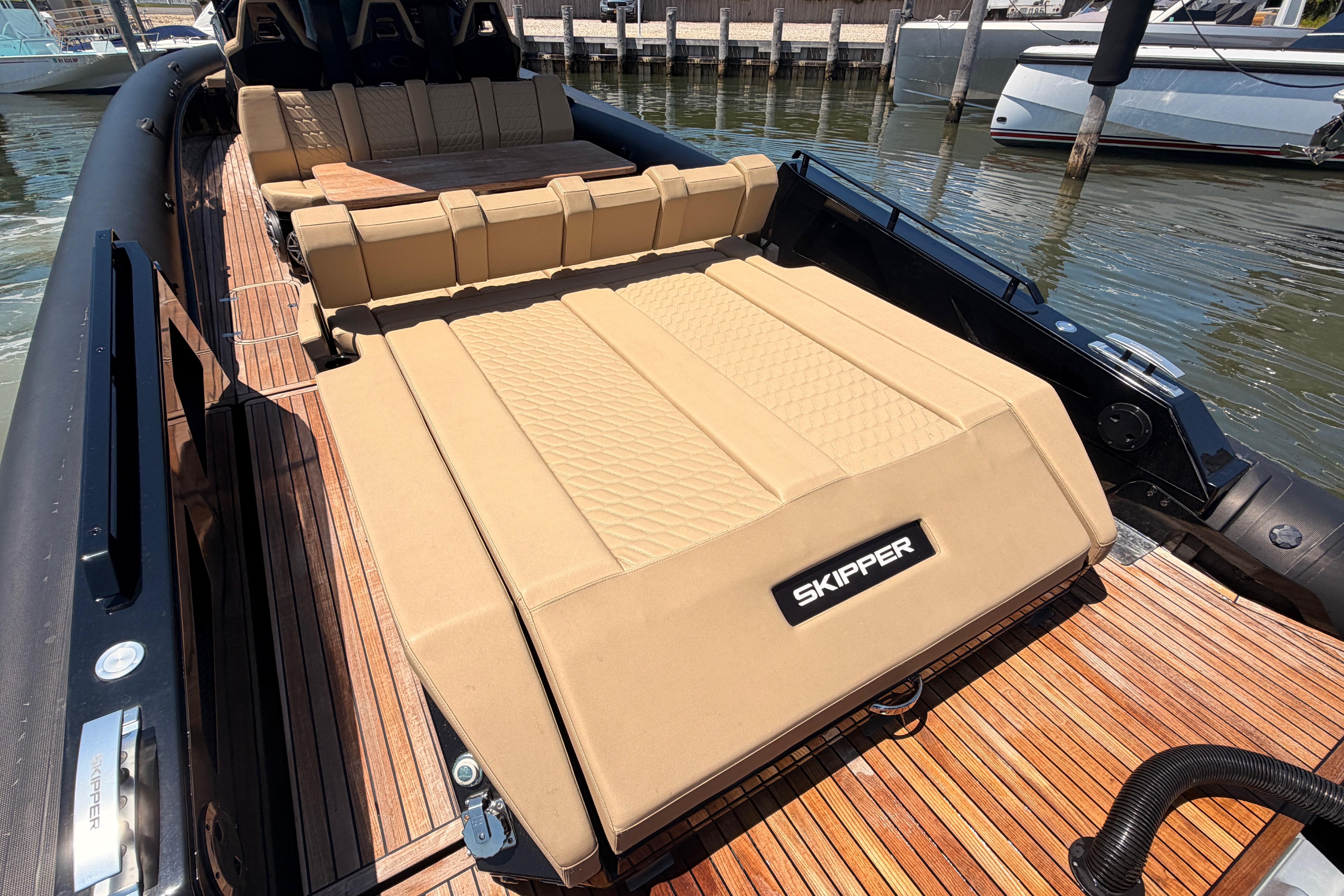 Luxurious 2023 Skipper-BSK 42NC boat with tan seating and wooden deck, docked at marina.