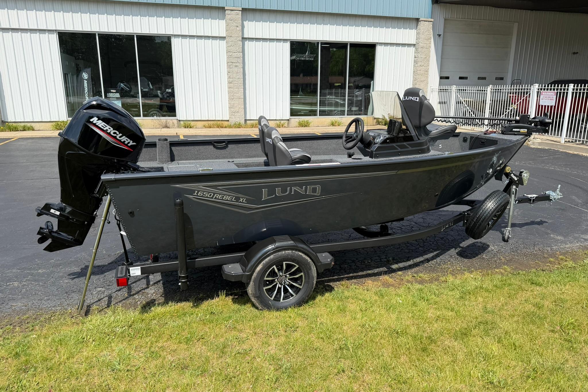 2027 Lund 1650 Rebel XL SS boat with Mercury engine on trailer, parked outdoors.