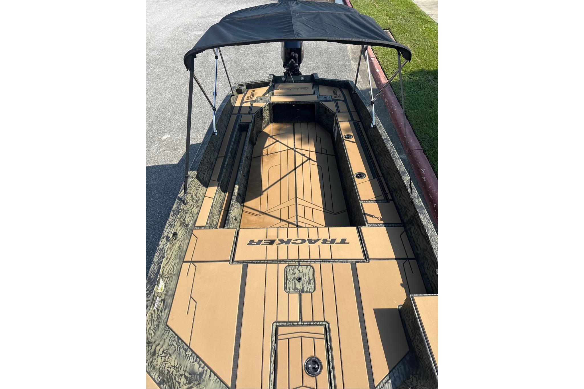 2026 Tracker Grizzly 1756 T Marsh boat with canopy, parked on pavement.