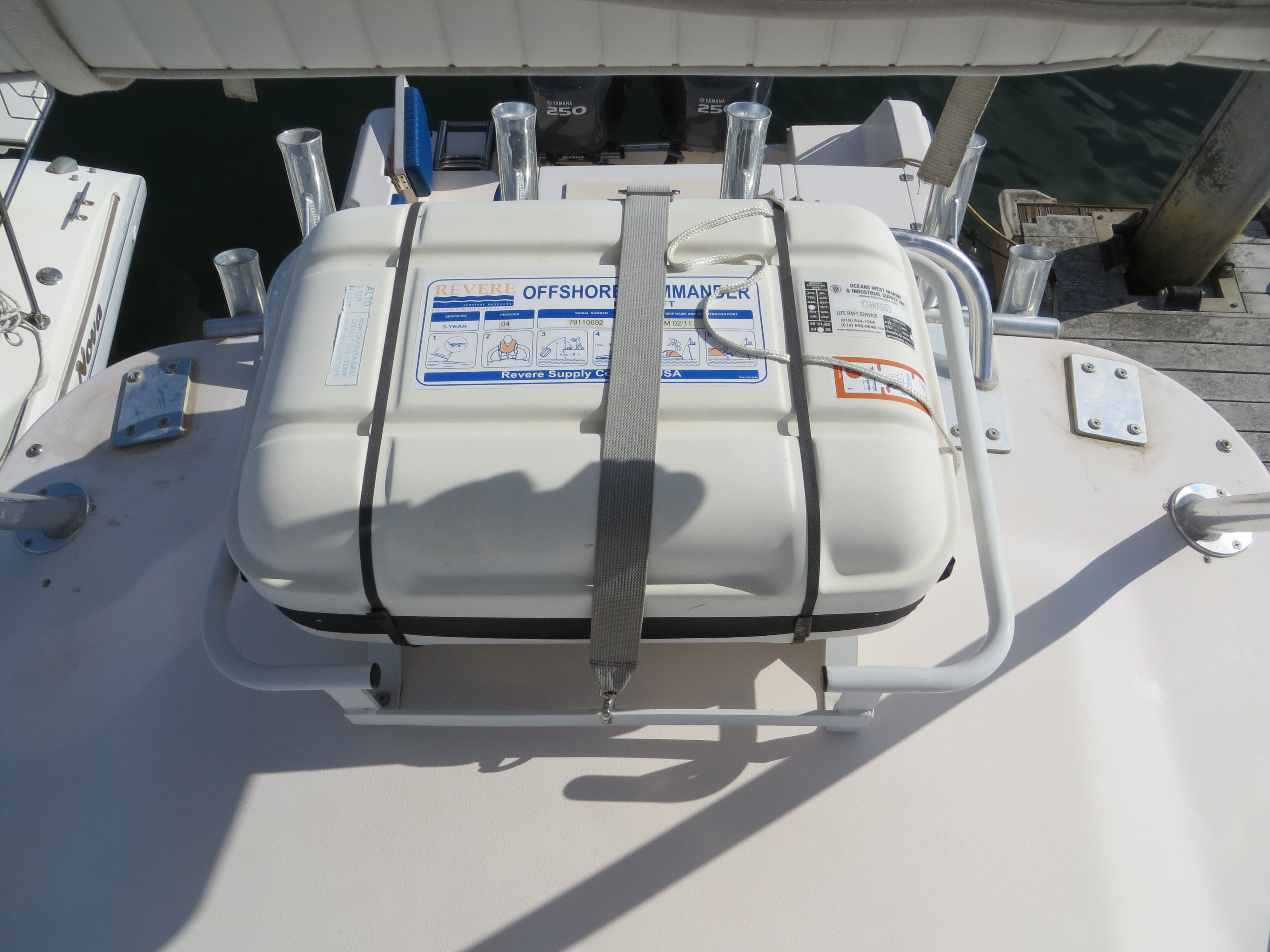 A liferaft is secured on a boat's deck, surrounded by fishing rod holders.
