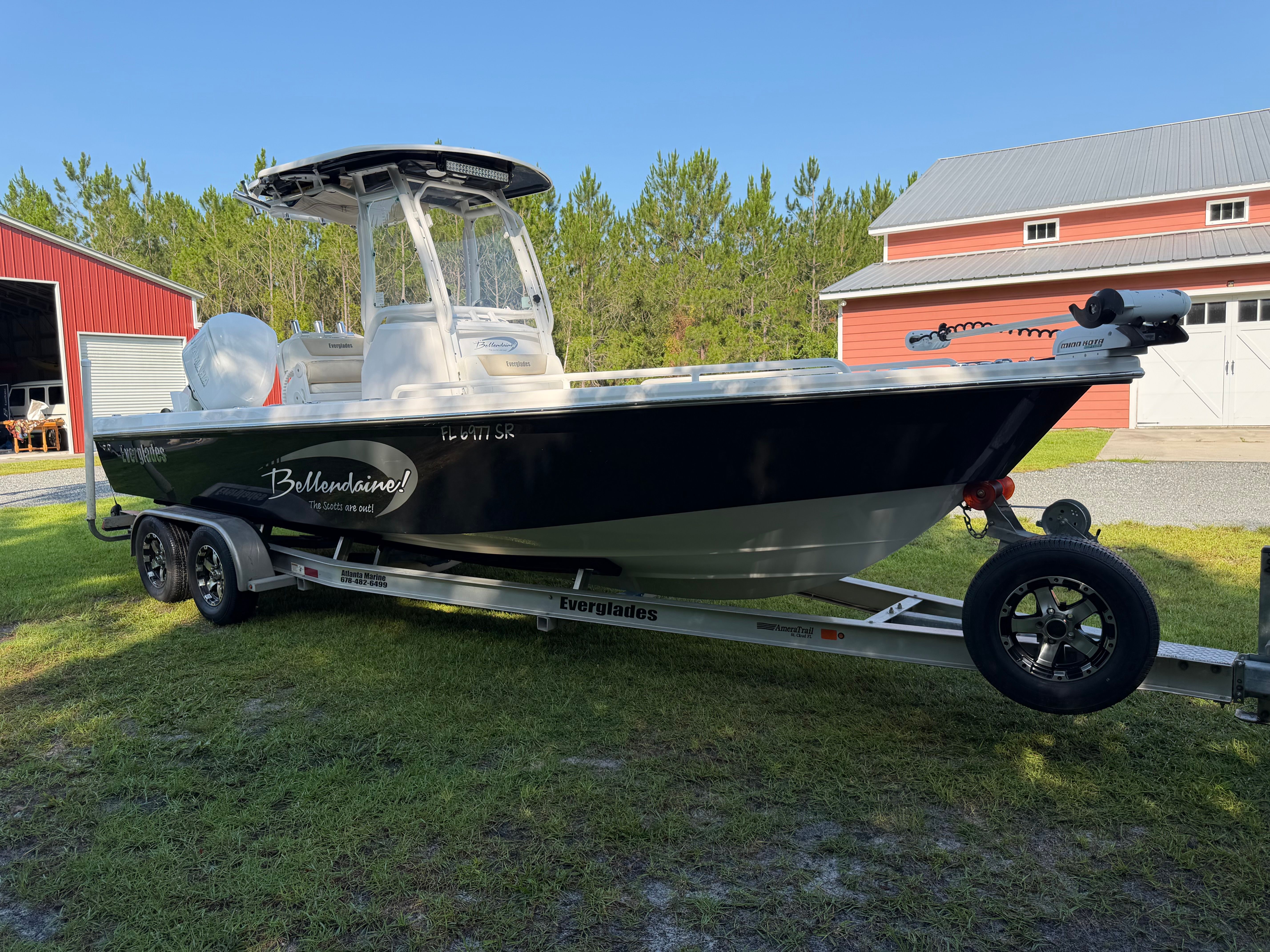 A 2016 Everglades 243 Center Console boat on a trailer in front of a barn.