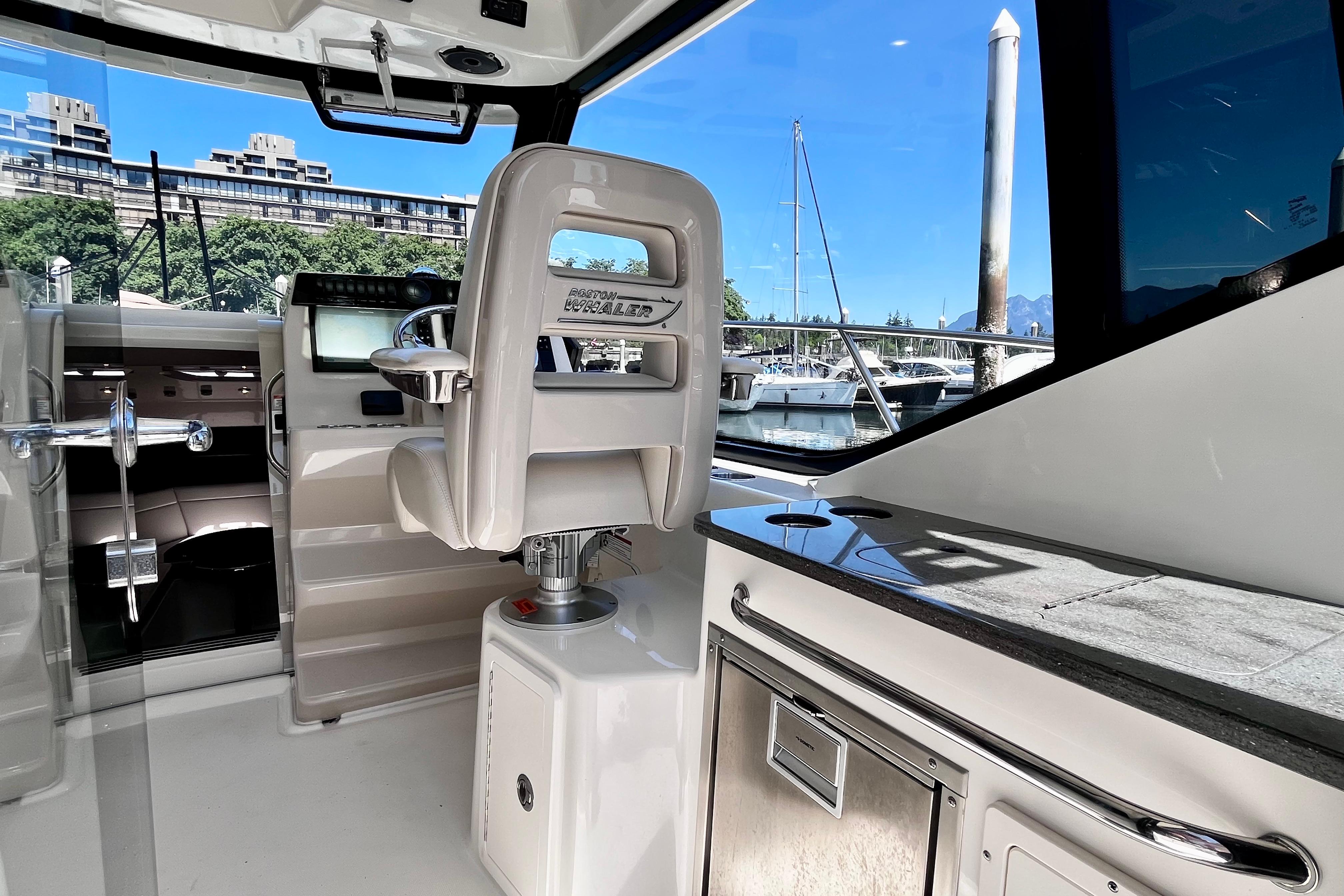 Interior of 2026 Boston Whaler 325 Conquest Pilothouse, featuring helm and marina view.