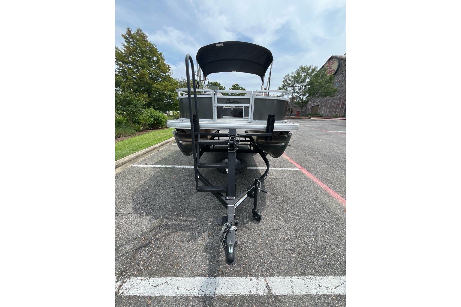 2026 Sun Tracker Bass Buggy 16 XL Select pontoon boat on trailer in parking lot.