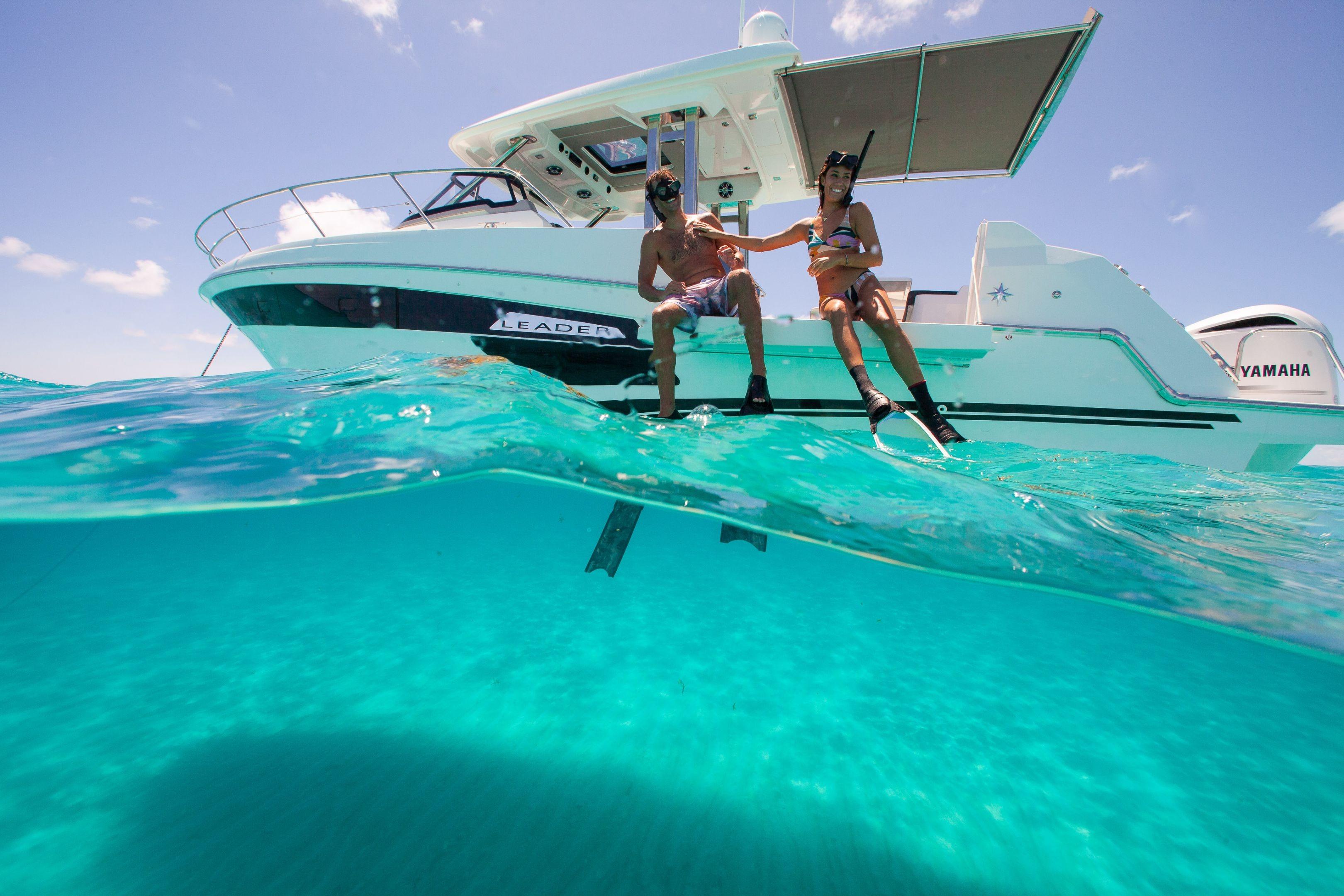 Couple enjoying snorkeling near Jeanneau Leader 12.5 WA boat in clear turquoise water.
