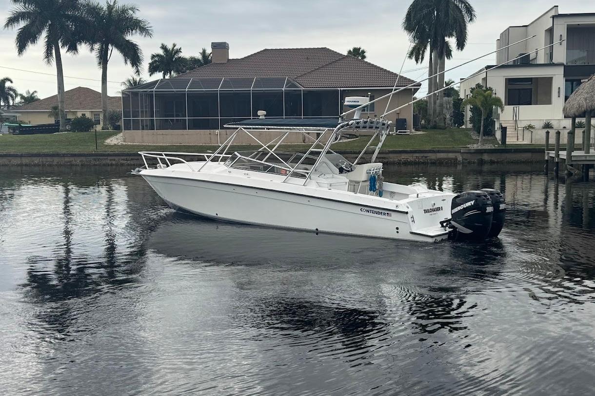 2001 Contender 35 Side Console boat on calm water near waterfront homes and palm trees.