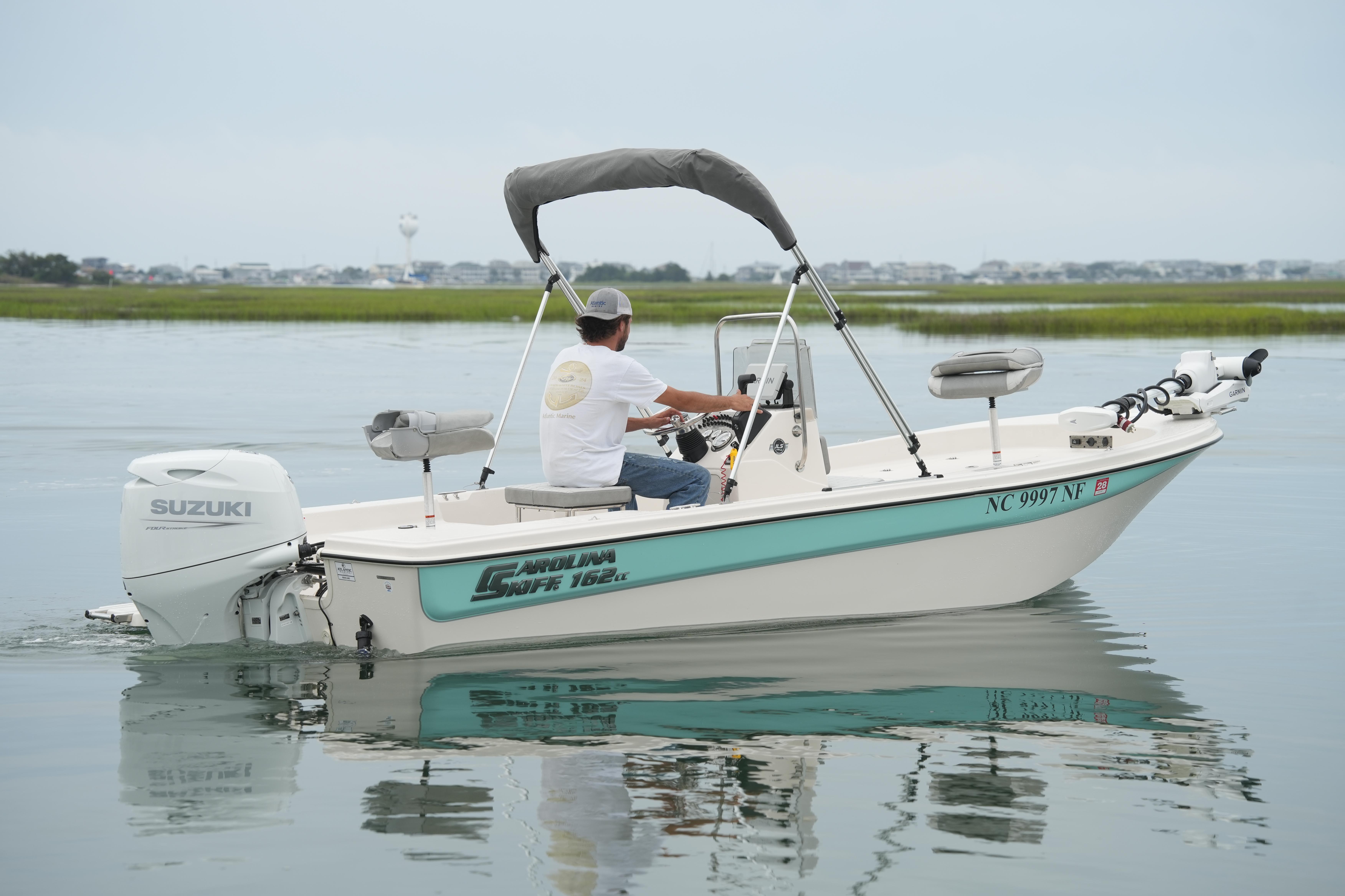2025 Carolina Skiff 162 JLS boat on calm water, featuring Suzuki outboard motor.