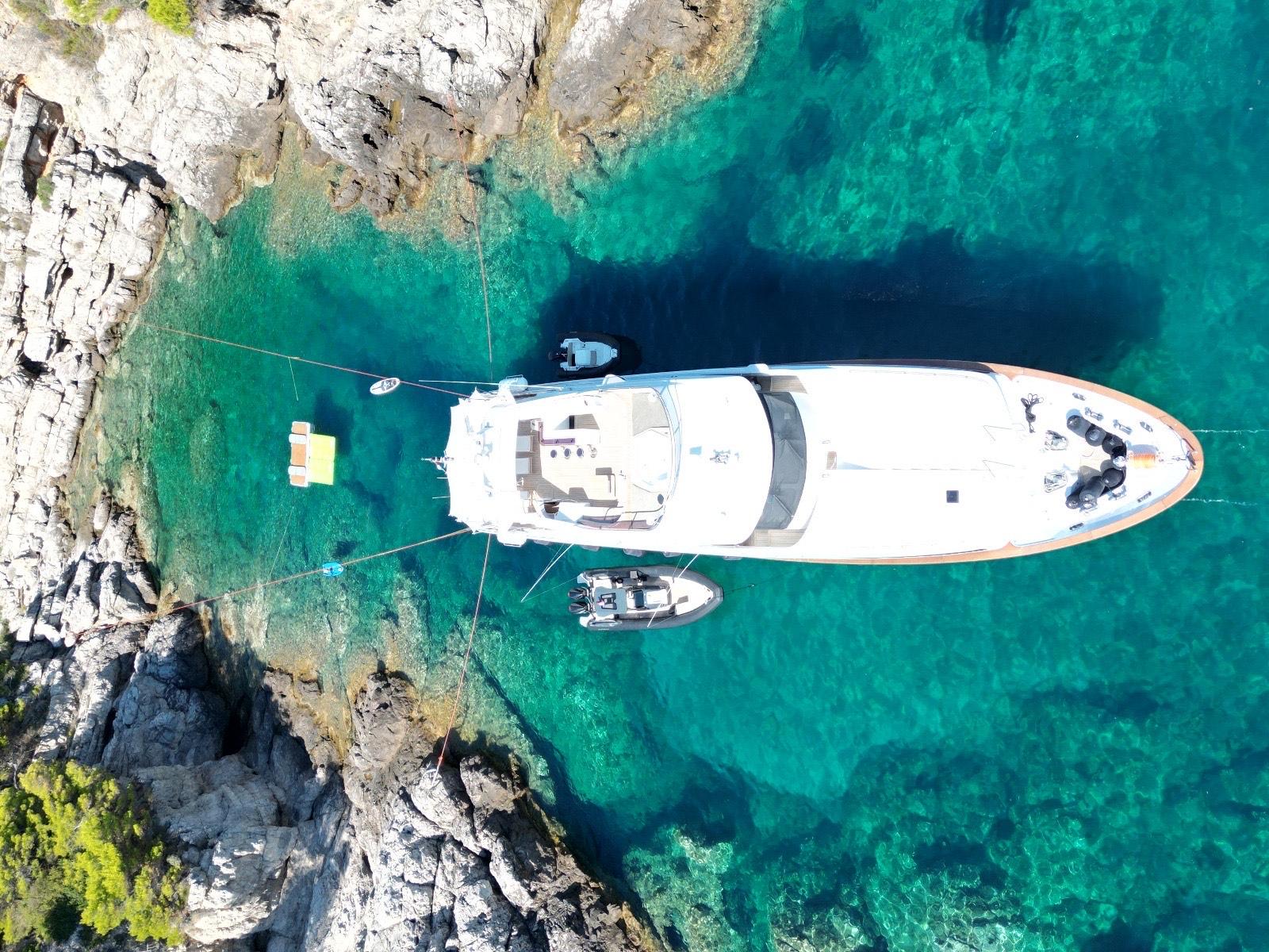 Aerial view of 2000 Benetti Classic 115 yacht anchored in clear turquoise waters.