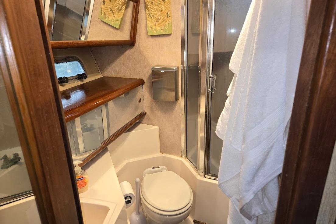 1987 Bayliner 4550 Motoryacht bathroom with shower, toilet, and wooden shelves.