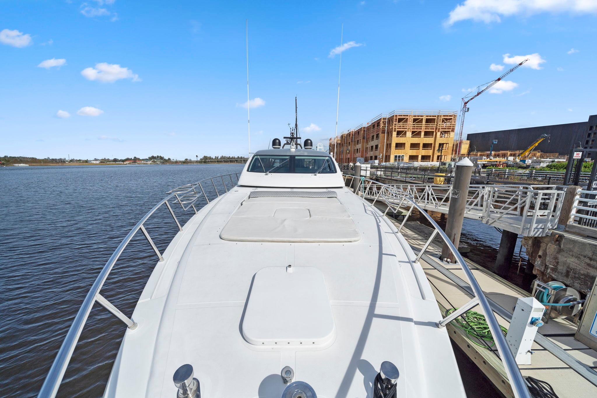 2010 Mangusta 72 Express yacht docked by waterfront construction site.