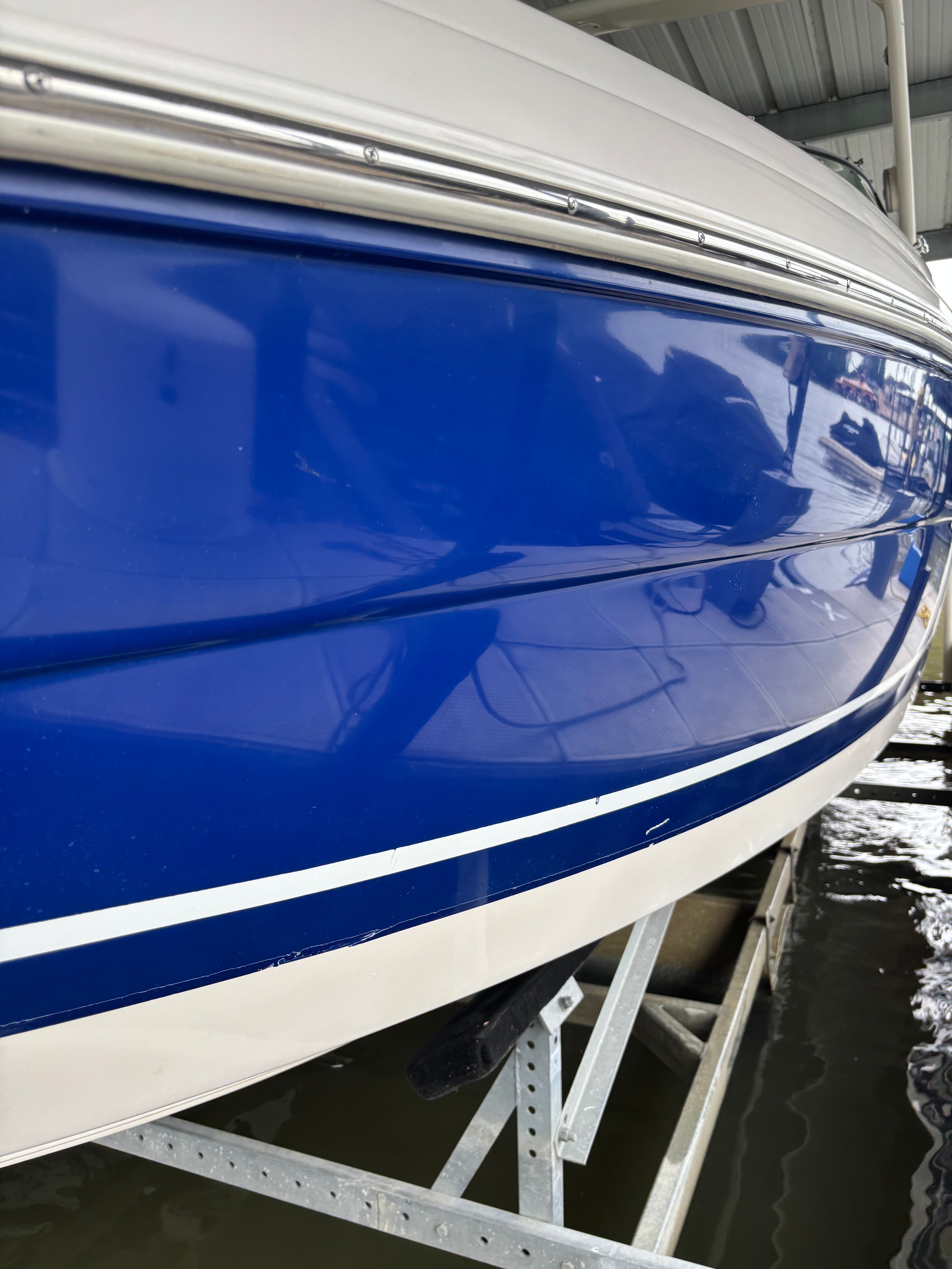 A blue and white 2006 Rinker 282 Captiva Bowrider is in a covered area.