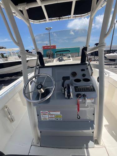 2022 Bayliner Trophy T22CC boat console with steering wheel and controls, docked under clear sky.