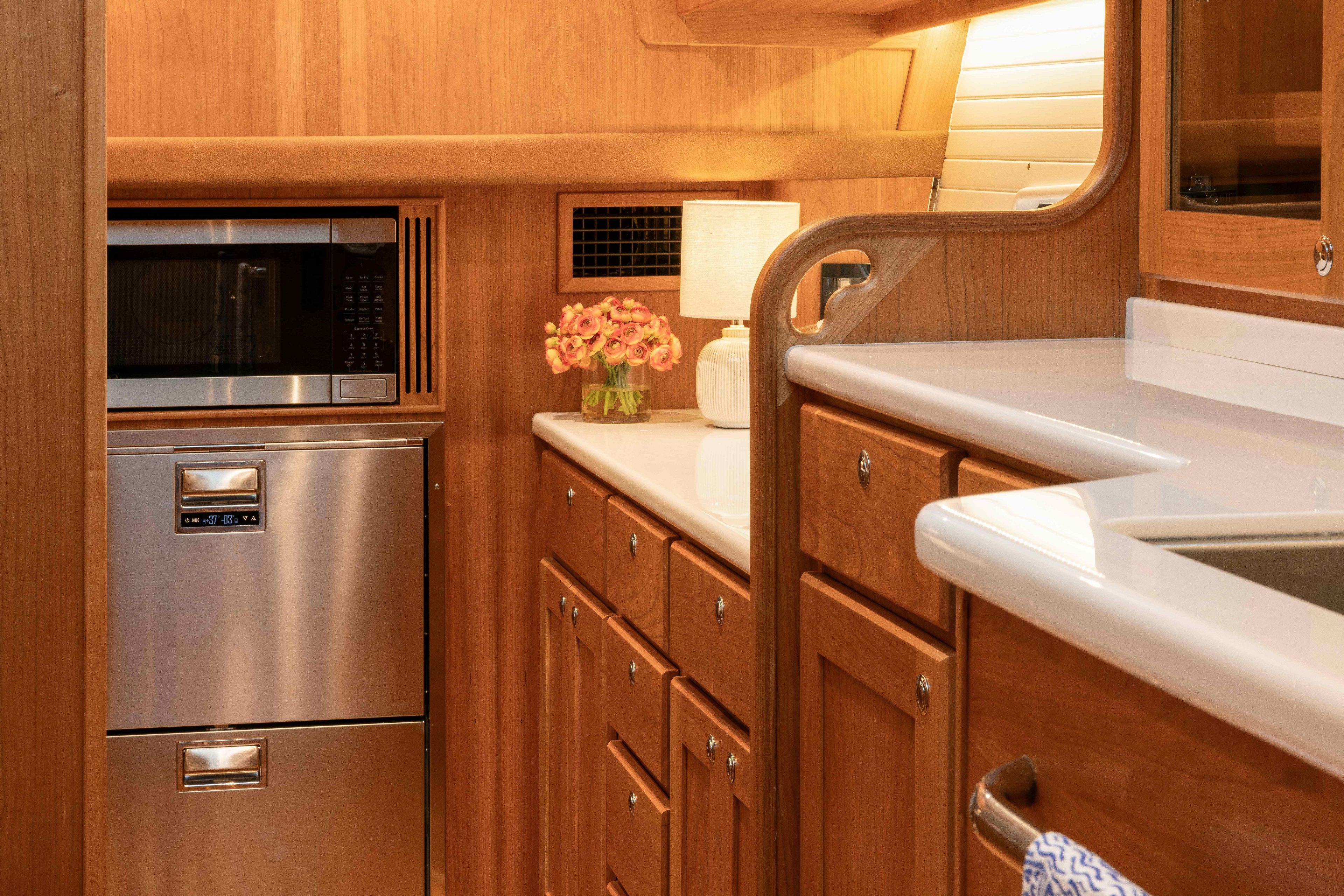 Luxurious 2027 Sabre 51 Salon Express yacht kitchen with wood cabinetry and modern appliances.