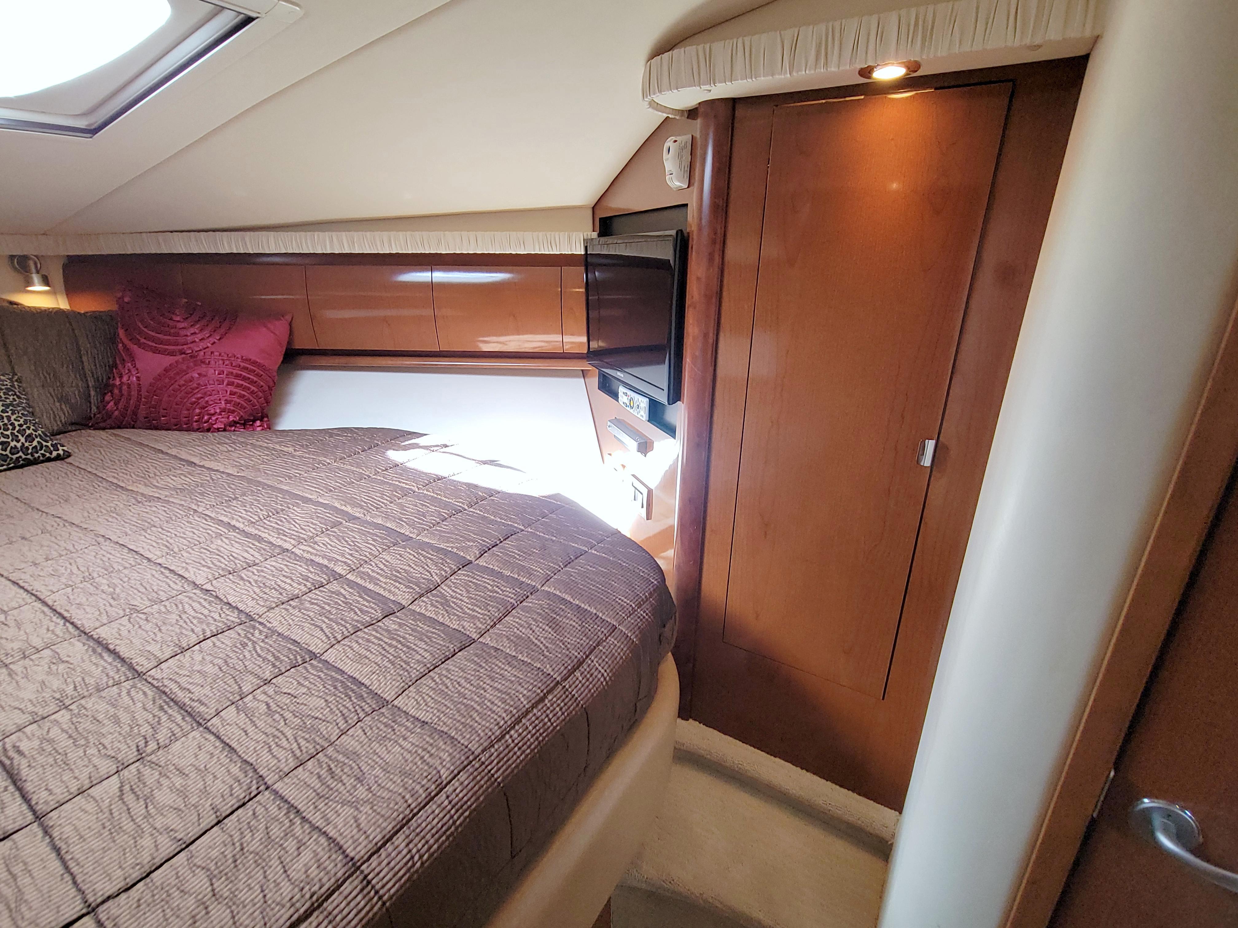 2009 Sea Ray 44 Sundancer cabin interior with bed, wooden cabinetry, and natural light.