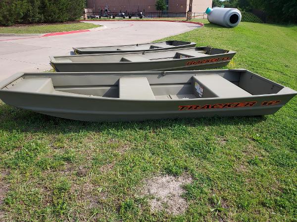 2025 Tracker Grizzly 1236 Utility boats on grass, ready for outdoor adventures.