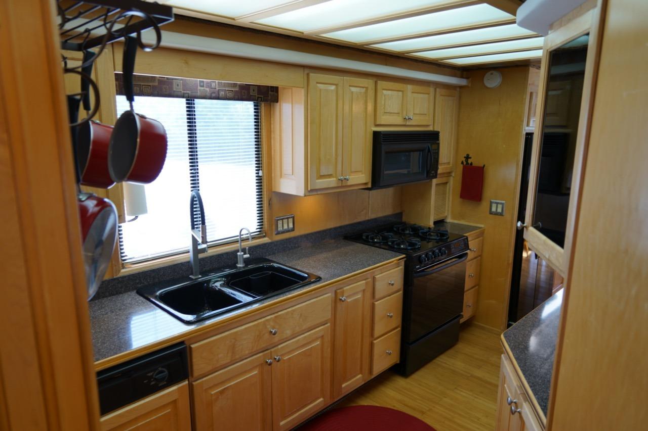 Kitchen interior of 2000 Stardust Cruisers houseboat, featuring wooden cabinets and modern appliances.