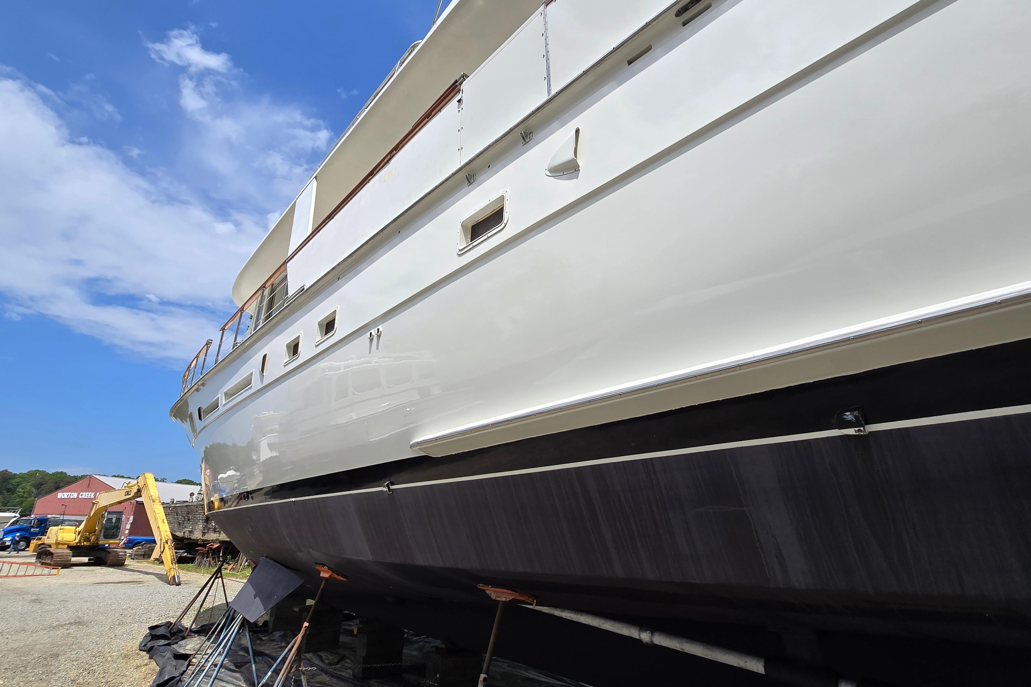 1980 Hatteras 70 Motor Yacht on dry dock under clear blue sky.