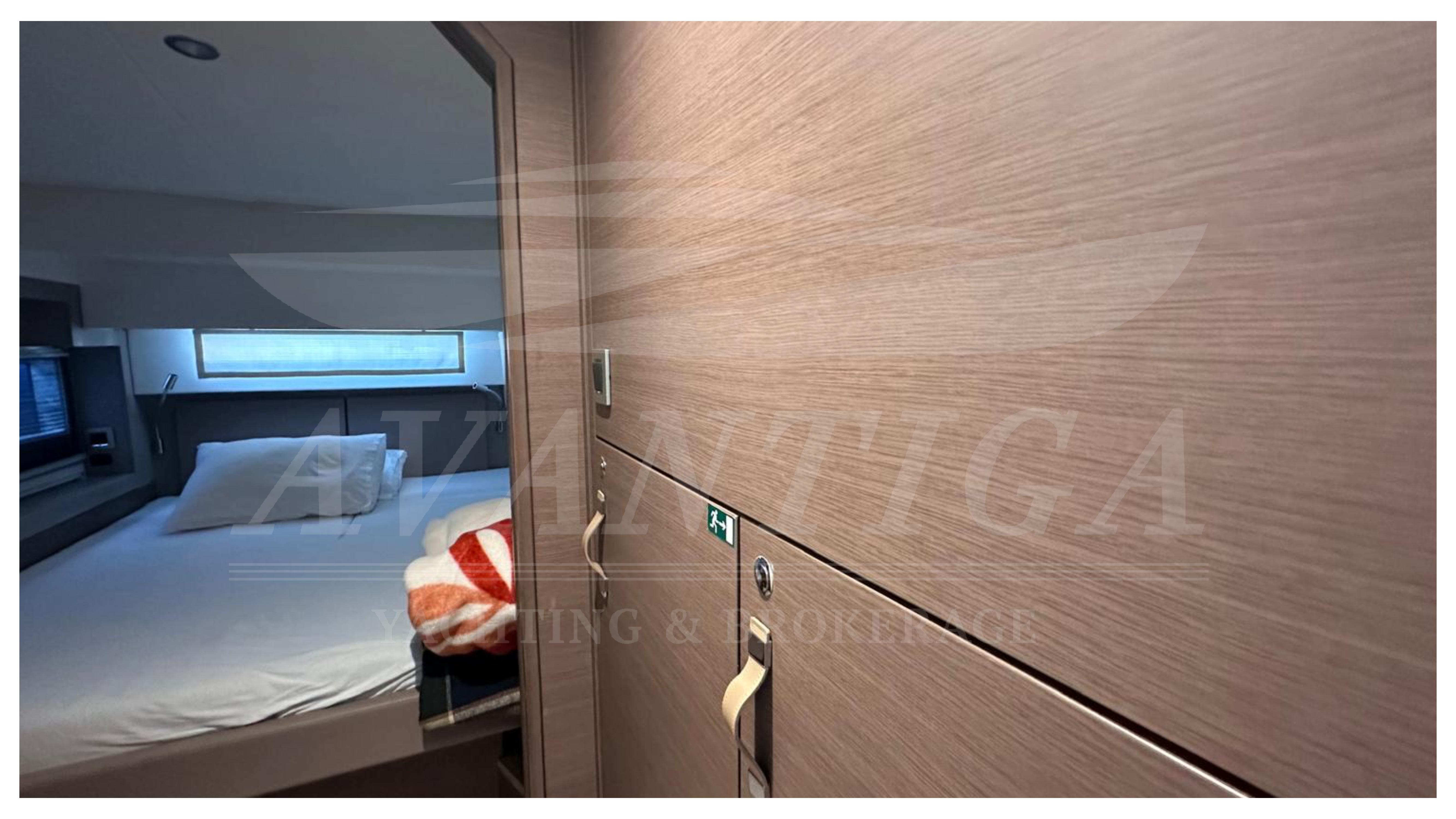 Interior of a 2021 Bali 4.2 yacht cabin with bed and wooden paneling.