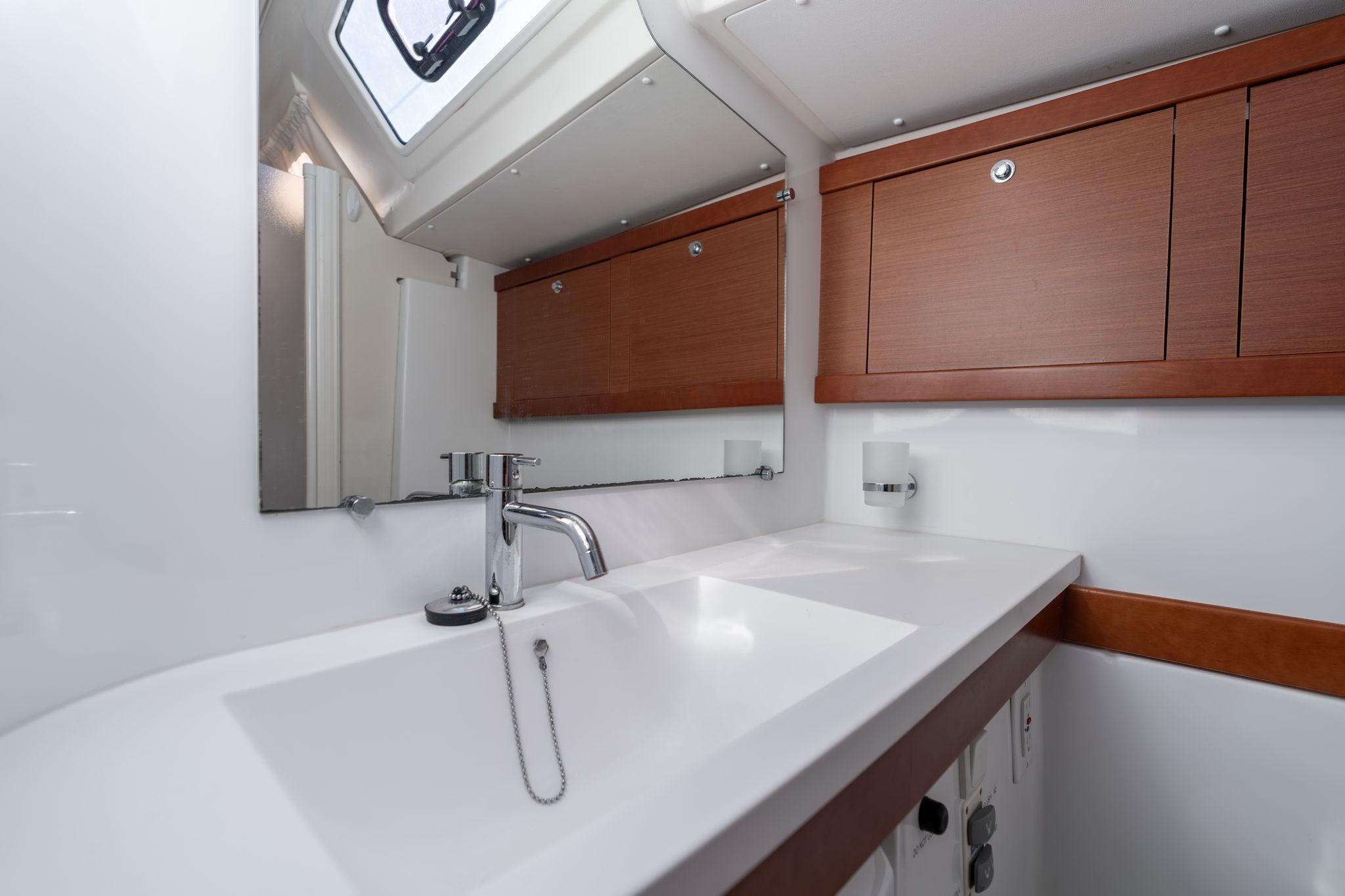 Modern bathroom interior of 2013 Beneteau Oceanis 50 yacht with sleek sink and wooden cabinets.