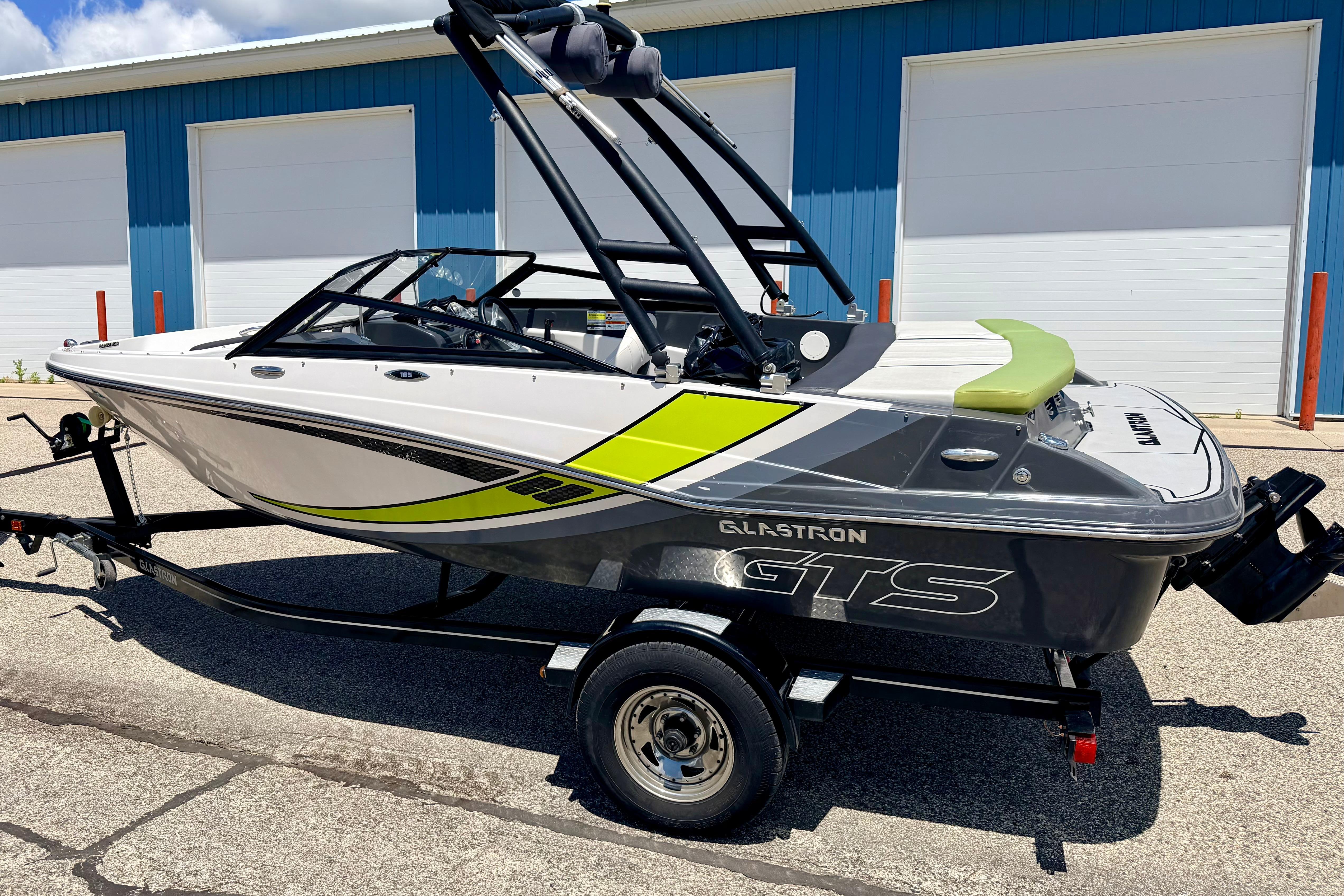 2018 Glastron GT 185 boat on trailer, parked outside blue building.