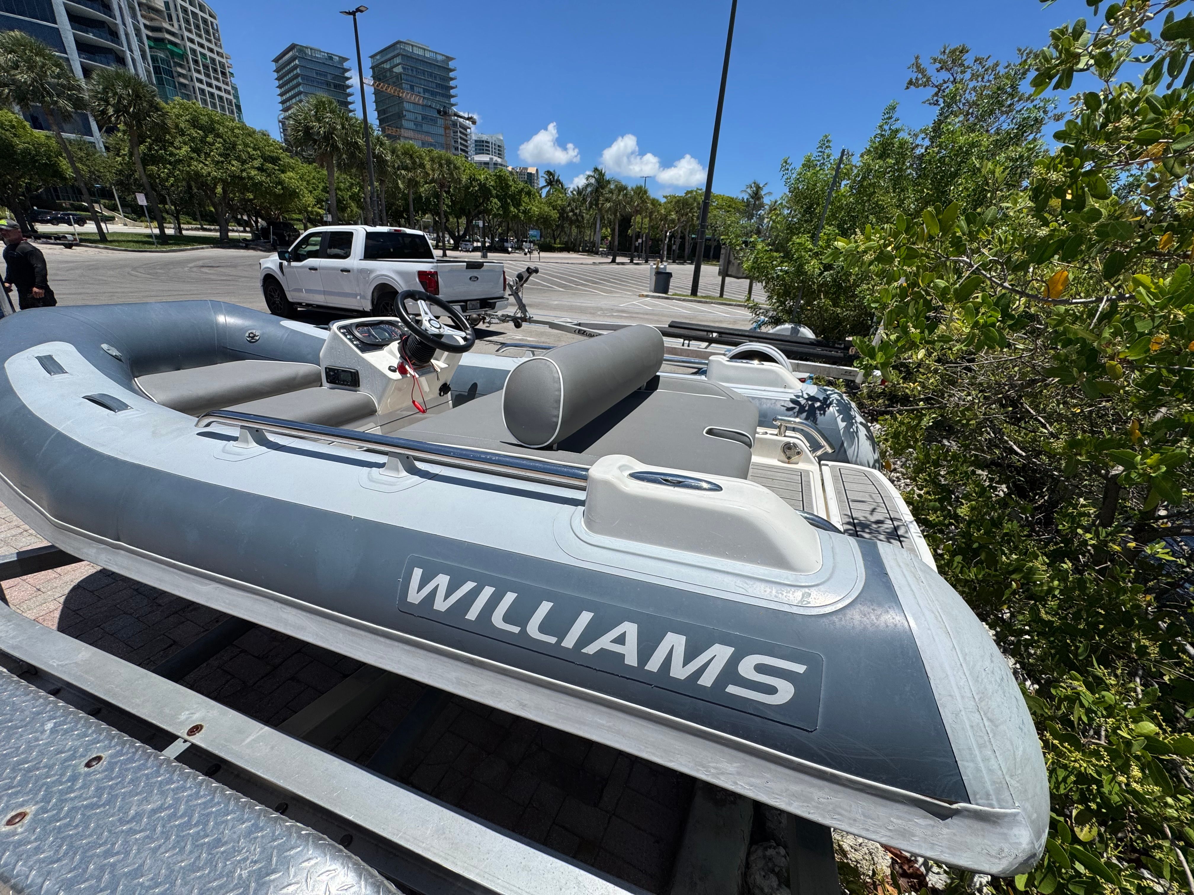 A gray Williams Jet Tender Sportjet 345 from 2019 is on a trailer in an urban setting.
