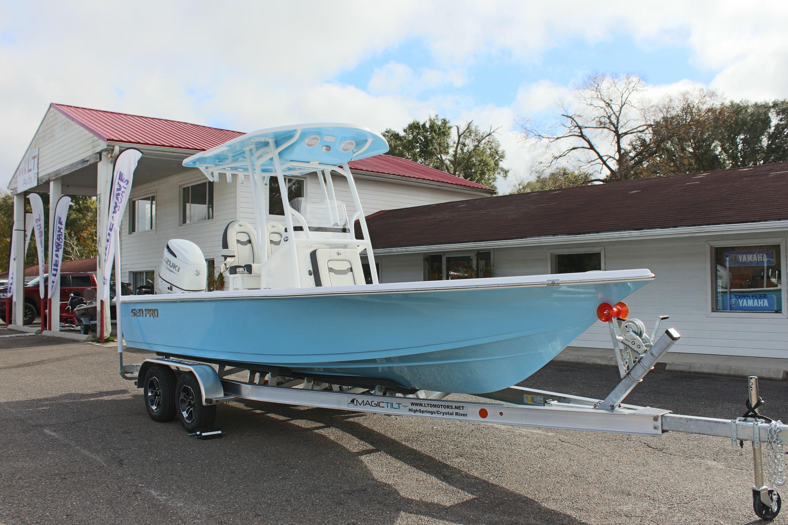 2025 Sea Pro 230 Bay boat on trailer outside dealership, featuring light blue hull.