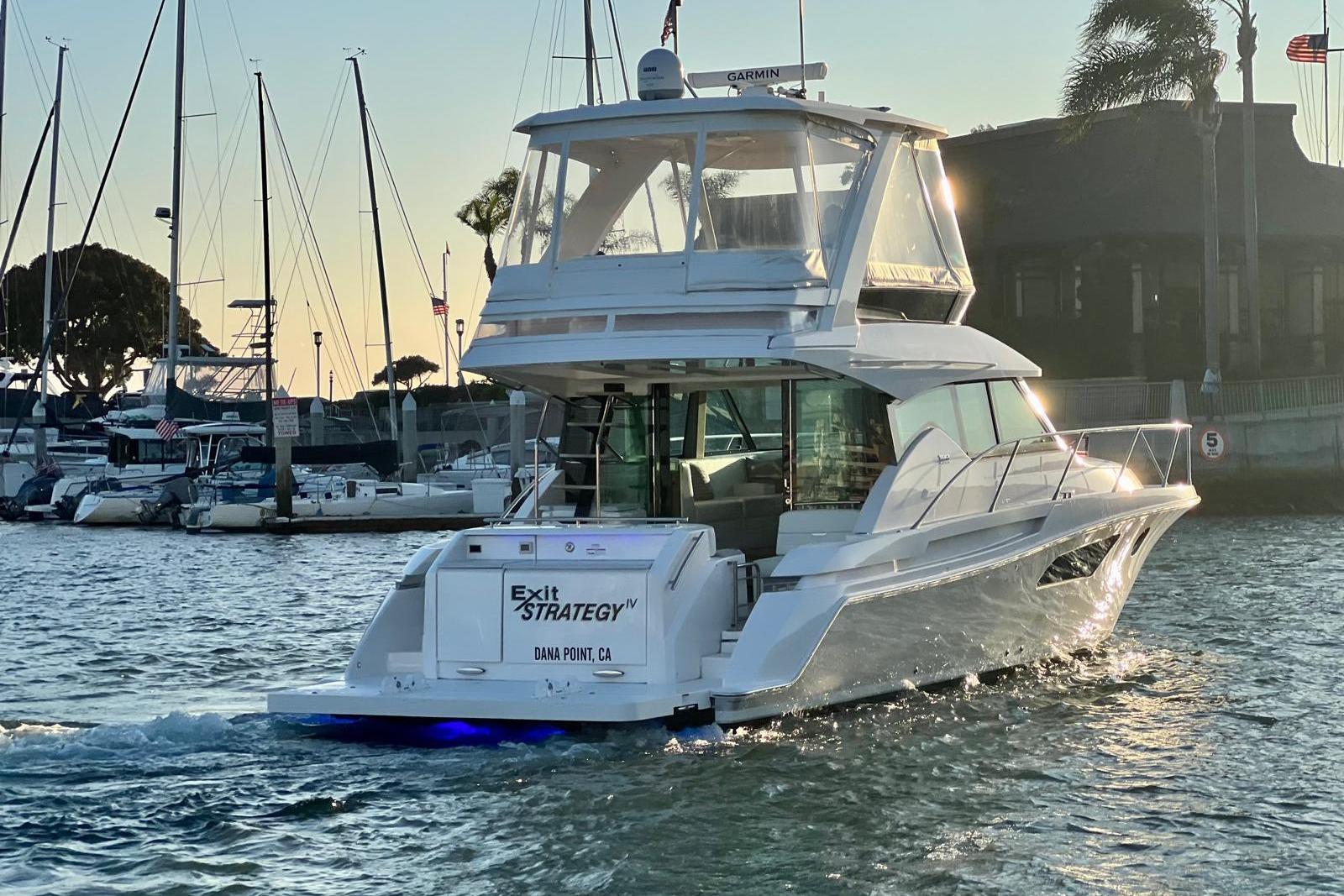 2019 Tiara Yachts F44 Flybridge cruising in marina at sunset, Dana Point, CA.
