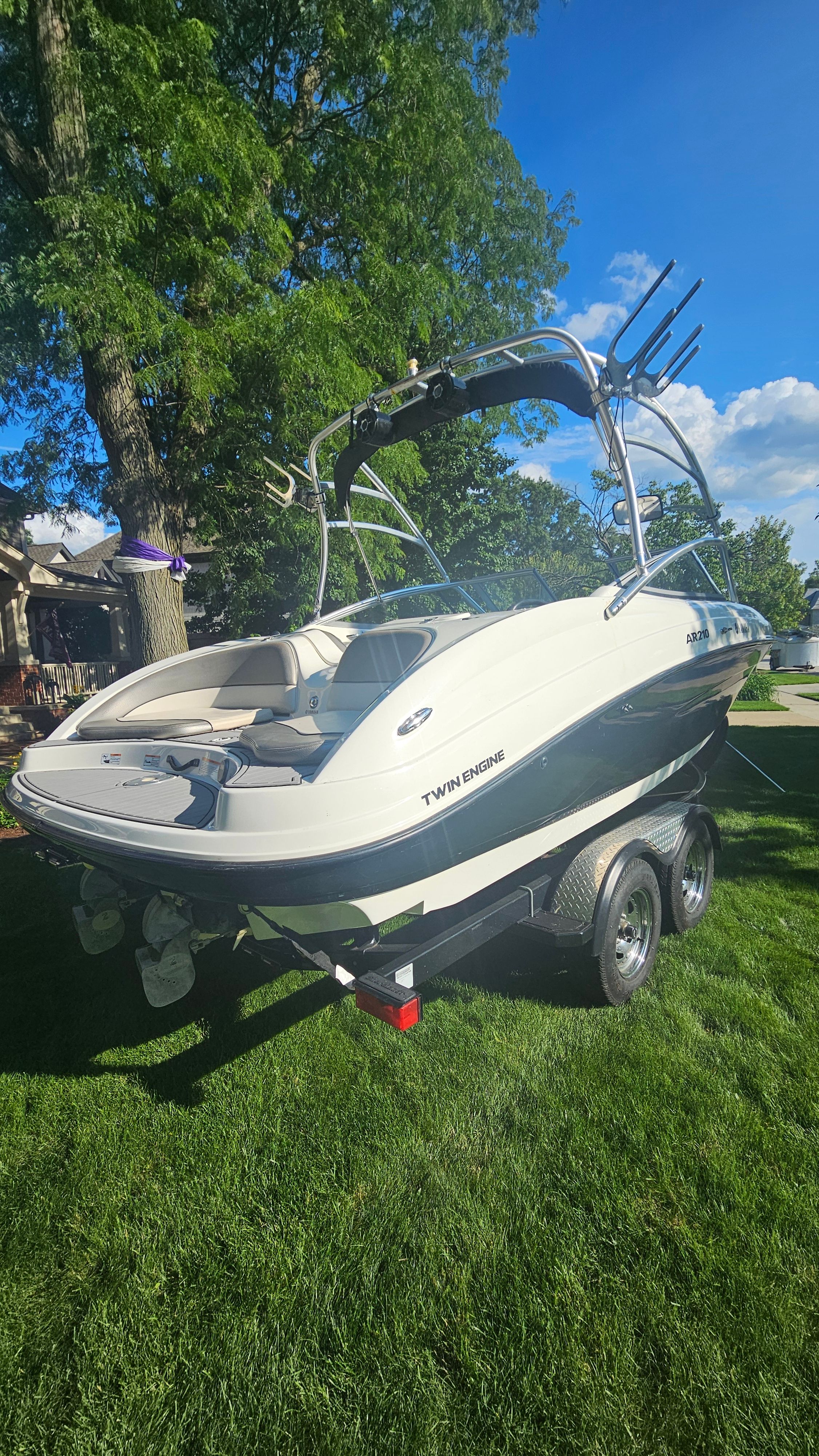 A 2010 Yamaha AR210 boat on a trailer, parked on a grassy lawn.