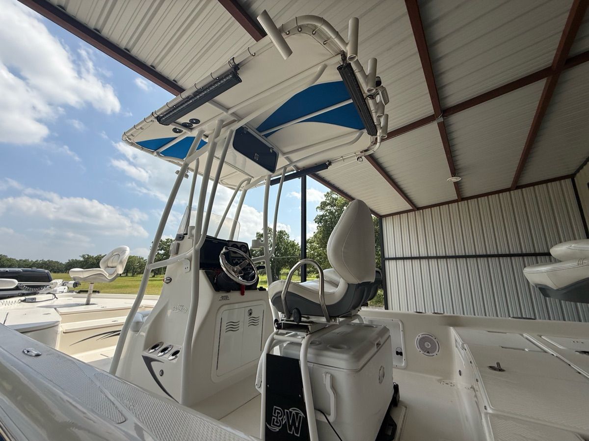 A 2016 Blue Wave 2400 PureBay boat in a covered area. It features a modern helm and seating.