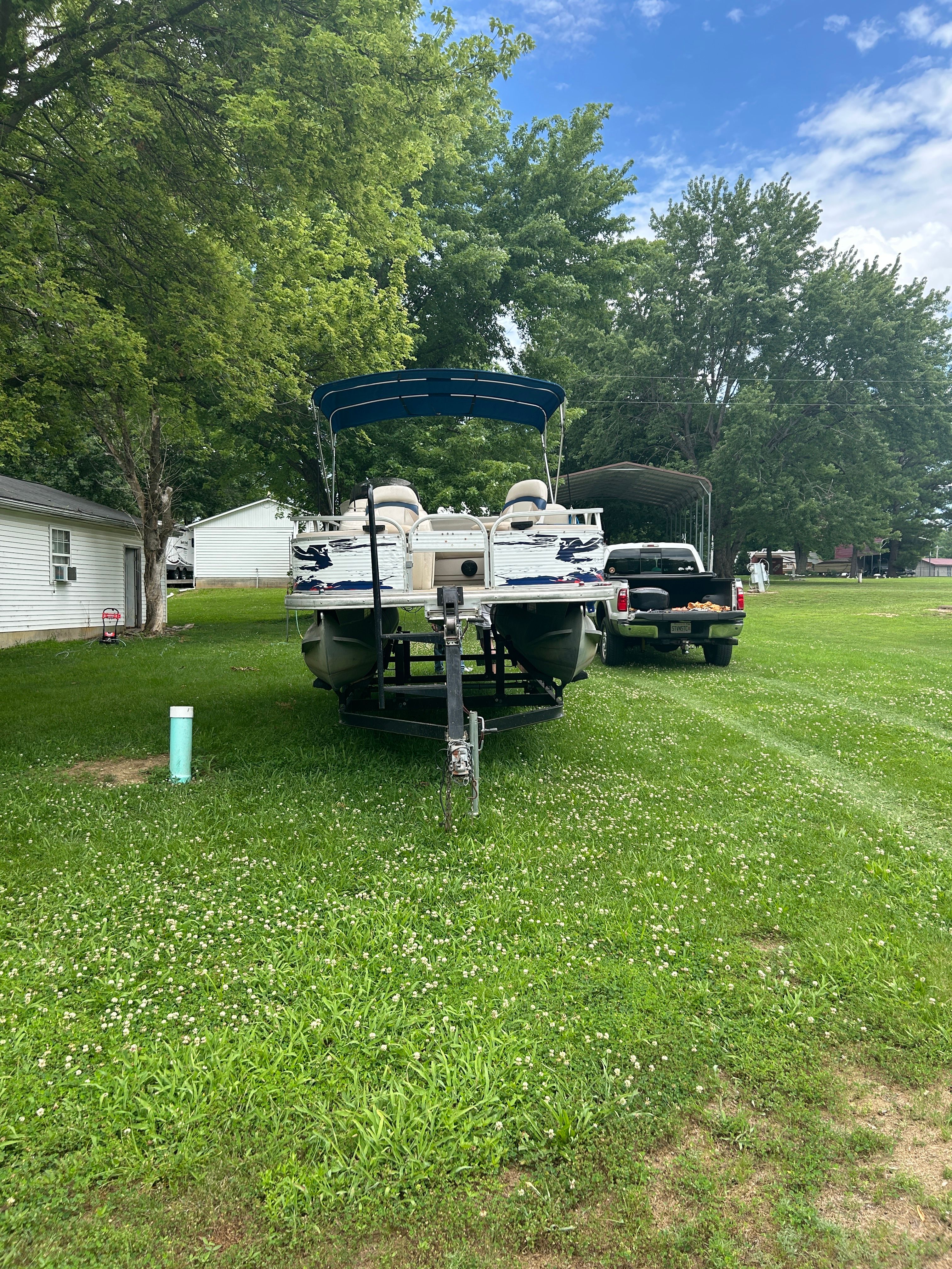 A 2008 Sun Tracker Fishin' Barge 21' on a trailer in a grassy area.