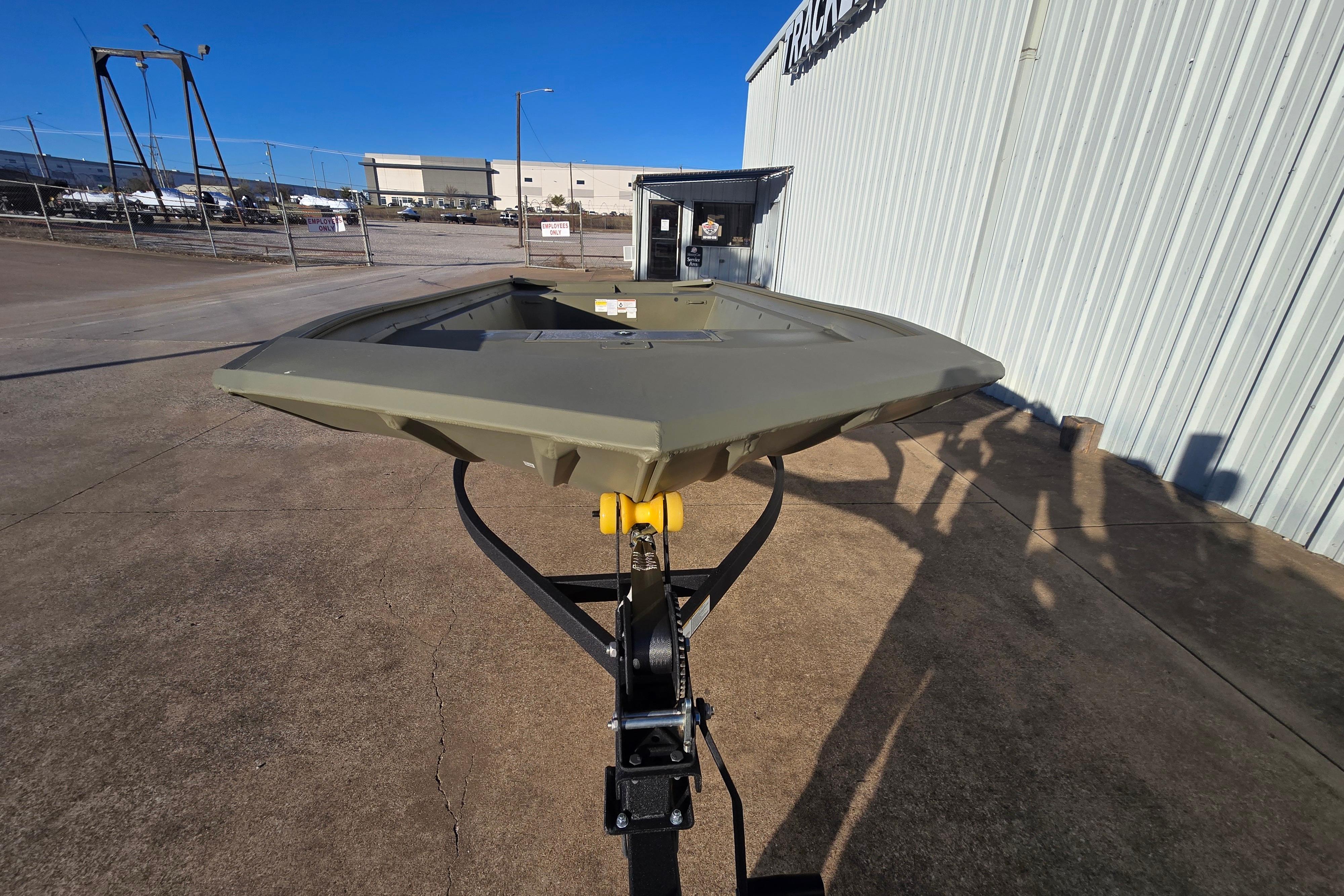 2025 Tracker Grizzly 1860 Utility boat on trailer outside industrial building.