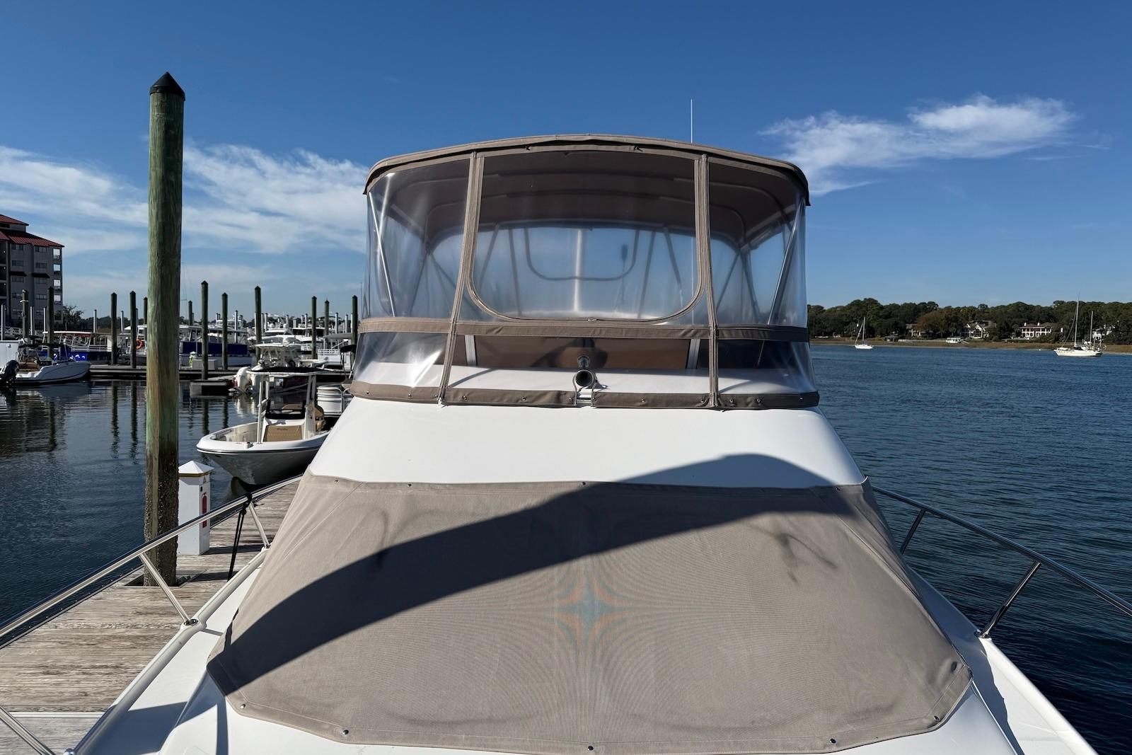 2003 Regal Commodore 3880 yacht docked at a marina under clear blue skies.