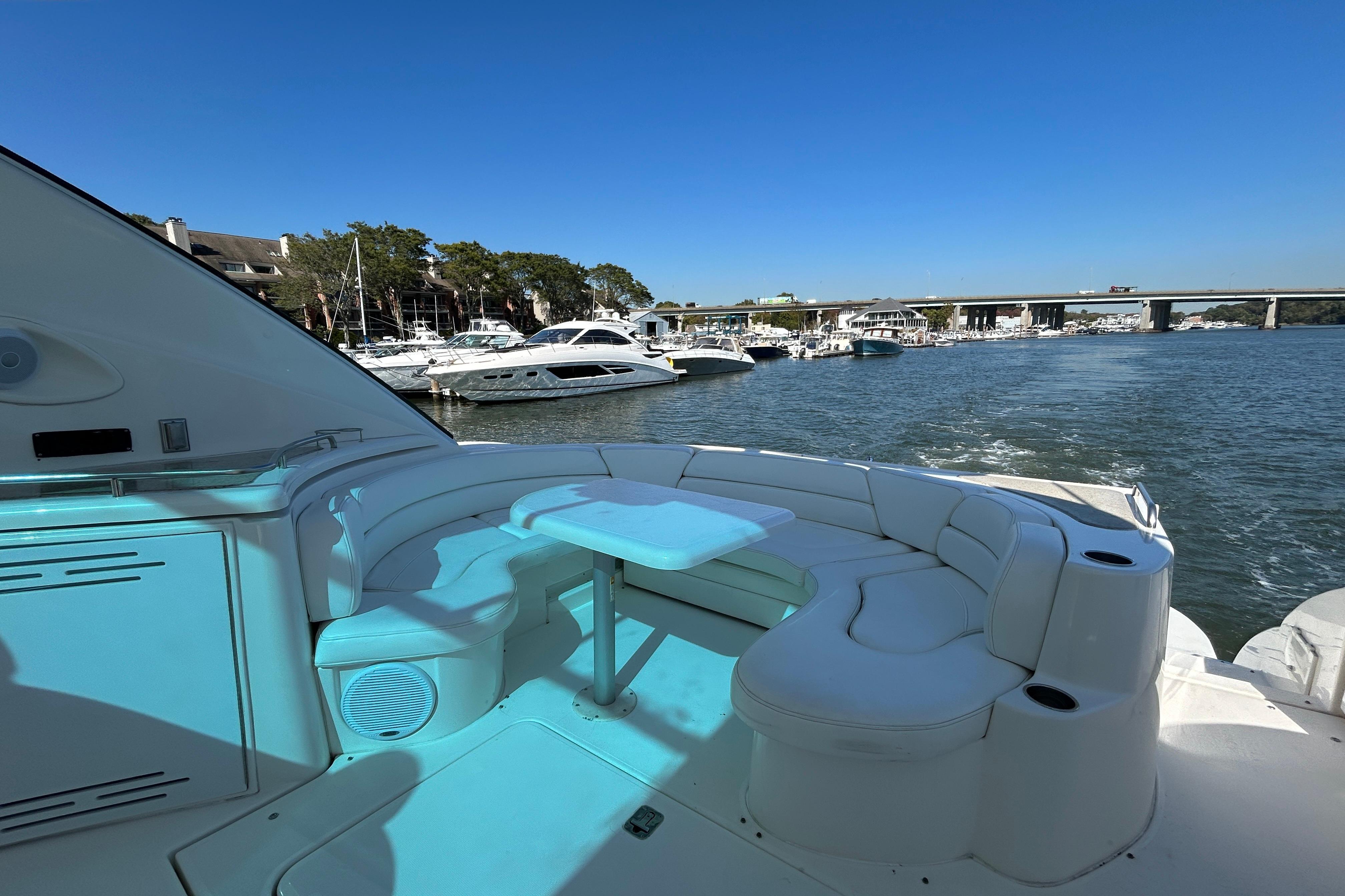 2003 Cruisers Yachts 540 Express with spacious seating, docked at a marina under clear blue skies.