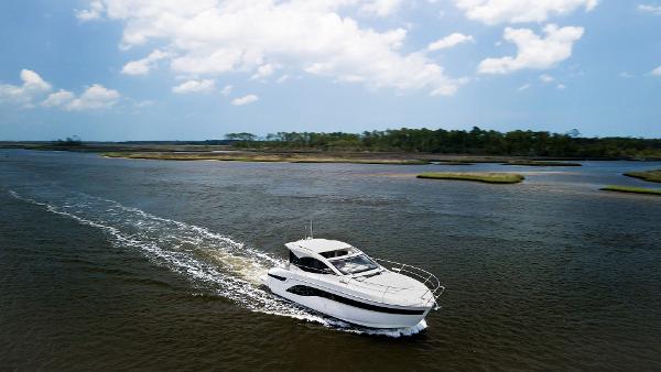 2022 Bavaria SR41 yacht cruising on a serene river under a partly cloudy sky.