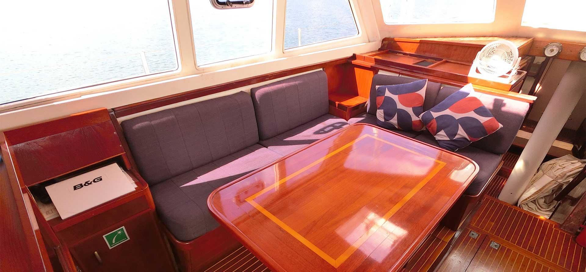 Interior of 1998 Colvin 85 Bermuda Rig Ketch with cozy seating and wooden table.