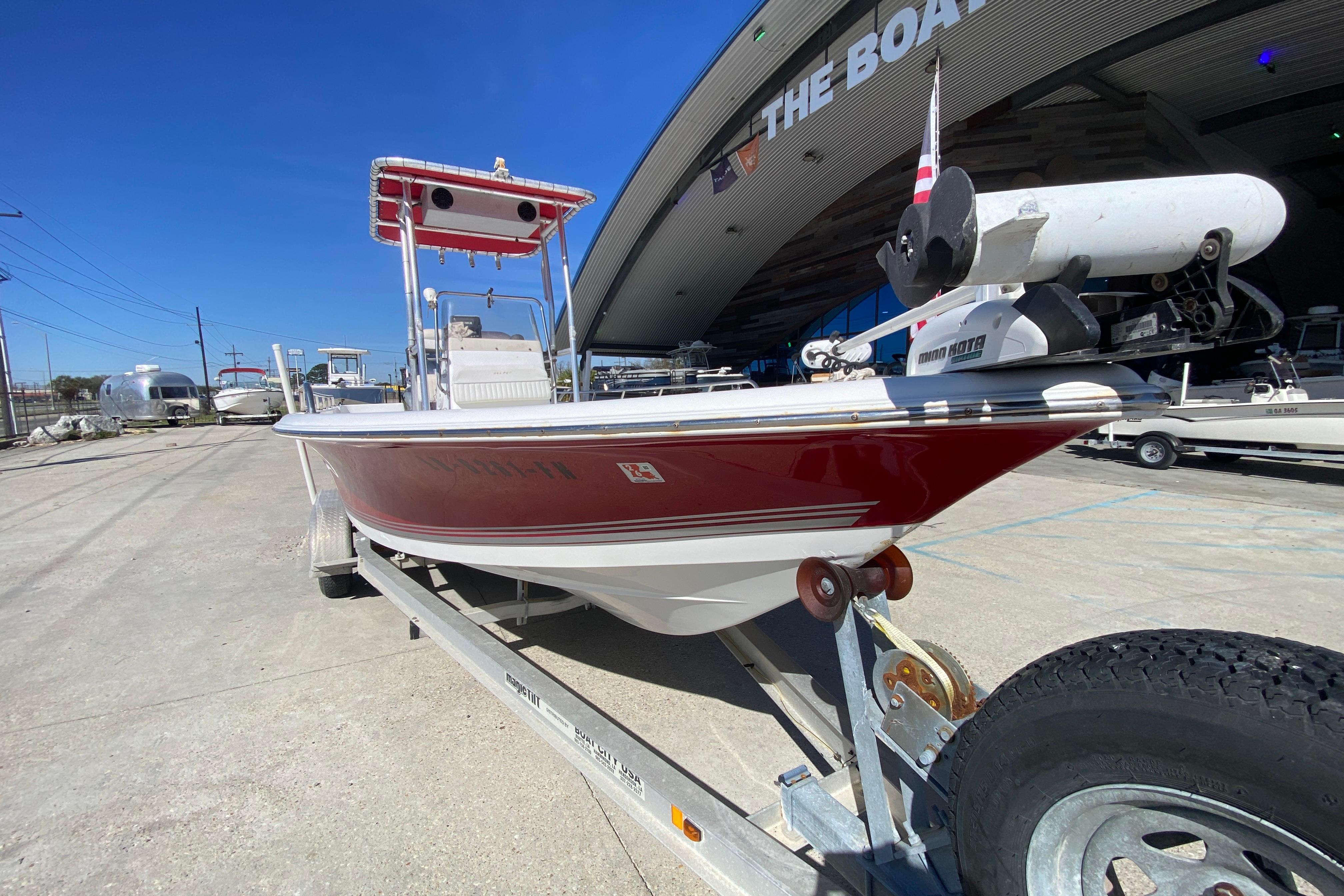 2005 Sea Pro SV2400CC Bay Boat on trailer, red hull, parked outside.