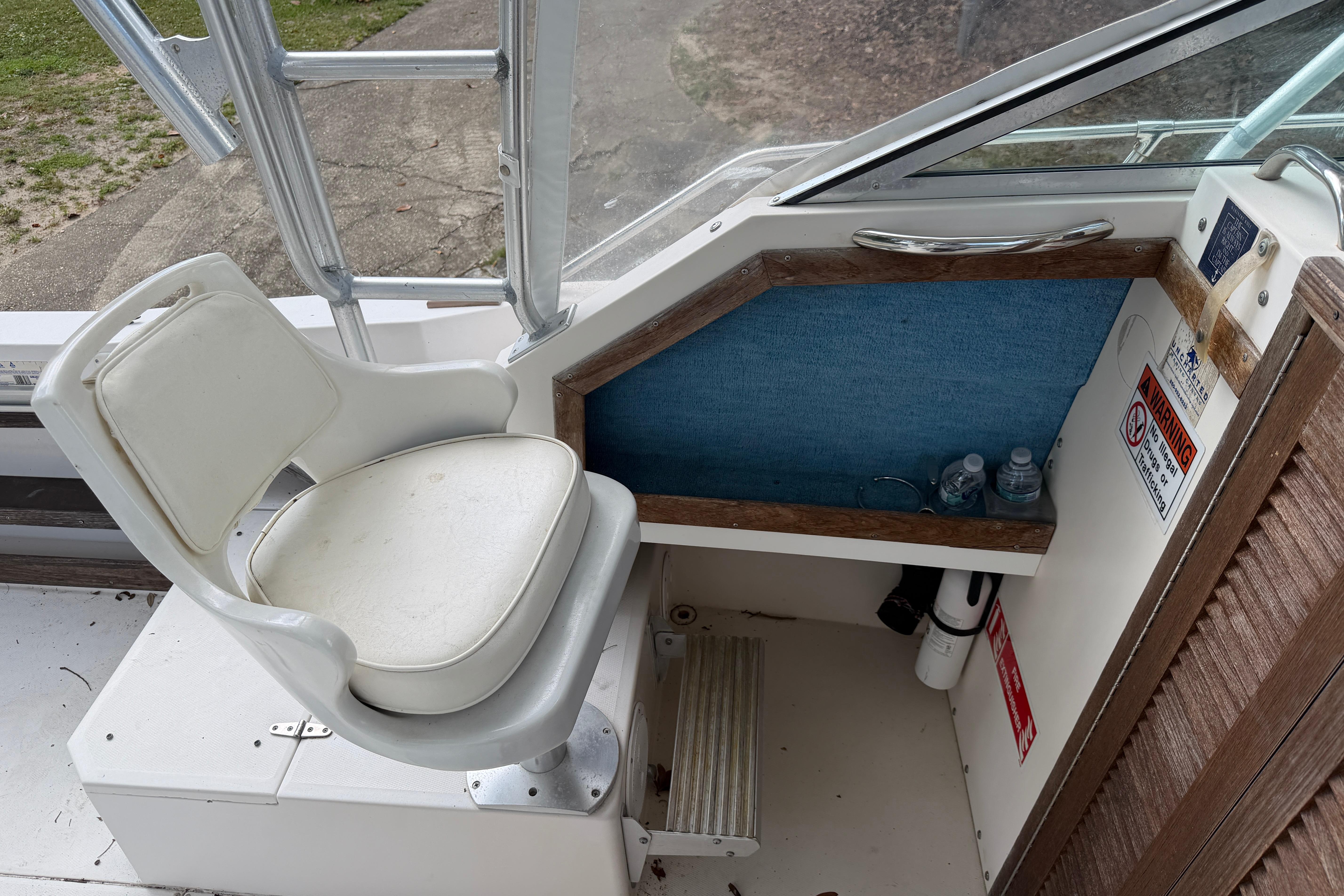 Captain's chair on 1987 Grady-White Seafarer 226 boat, featuring helm controls and storage area.