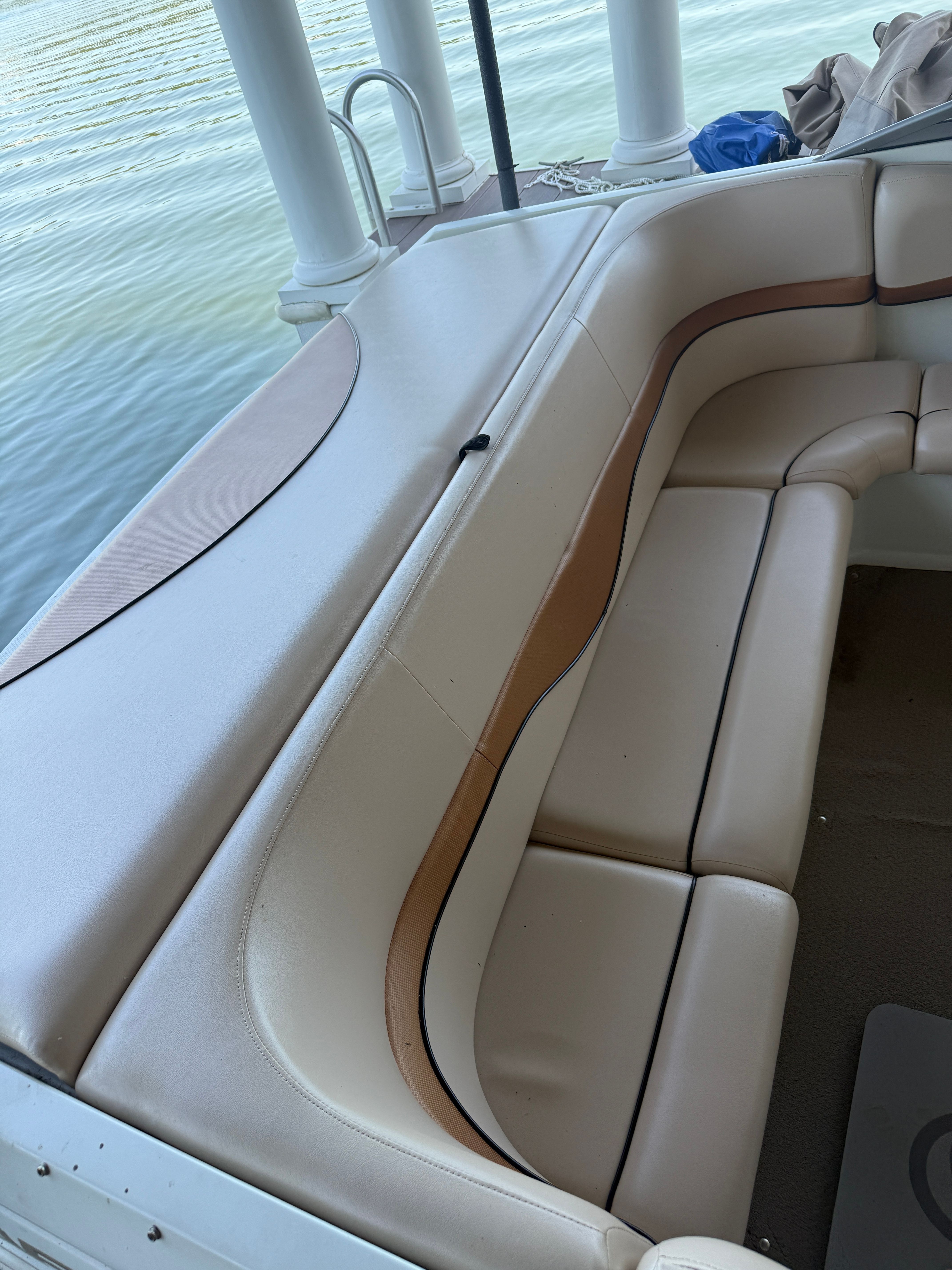 A cream-colored seating area on a boat docked by the water.