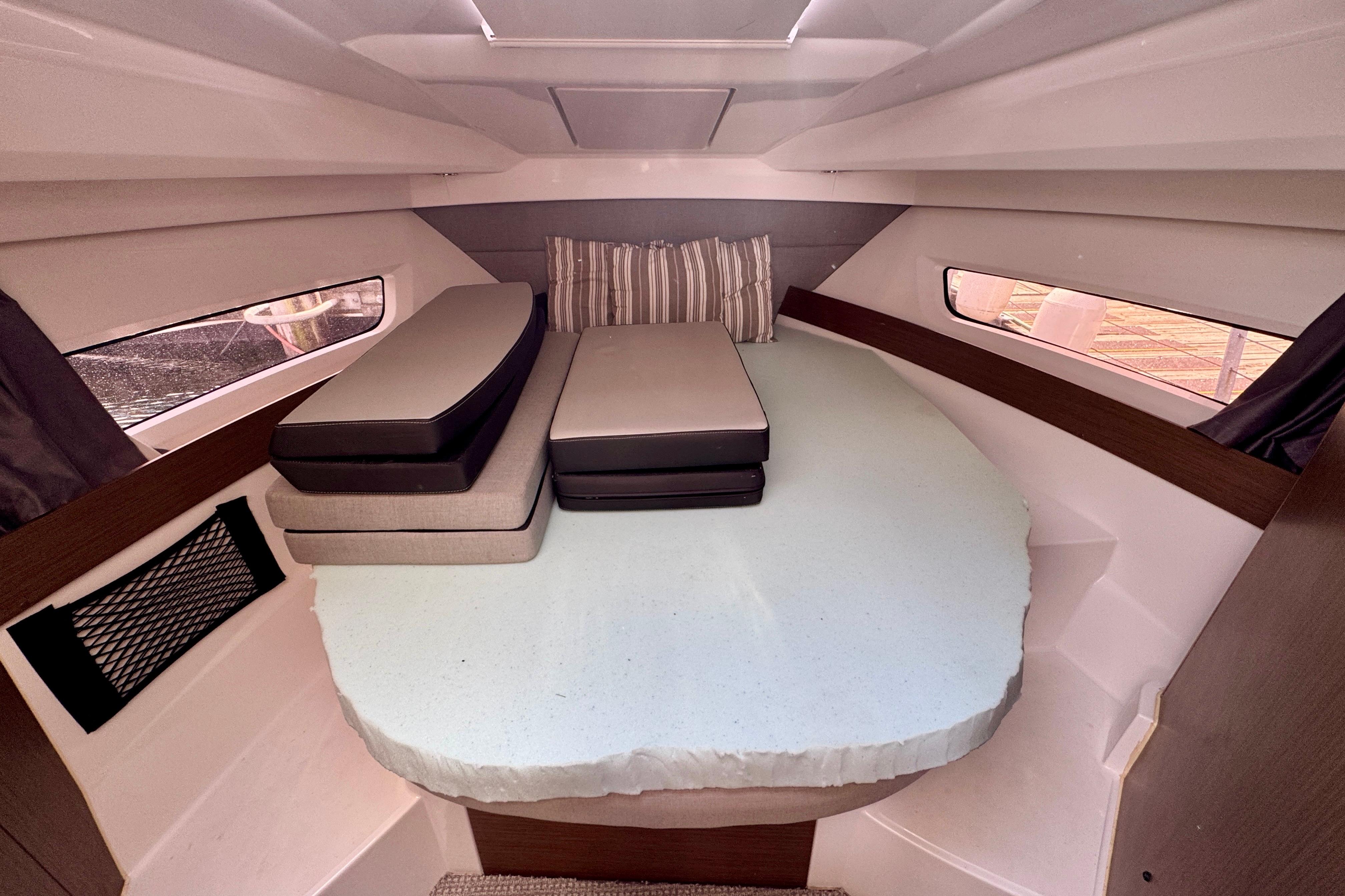 2020 Jeanneau NC 895 cabin interior with cushions and windows.