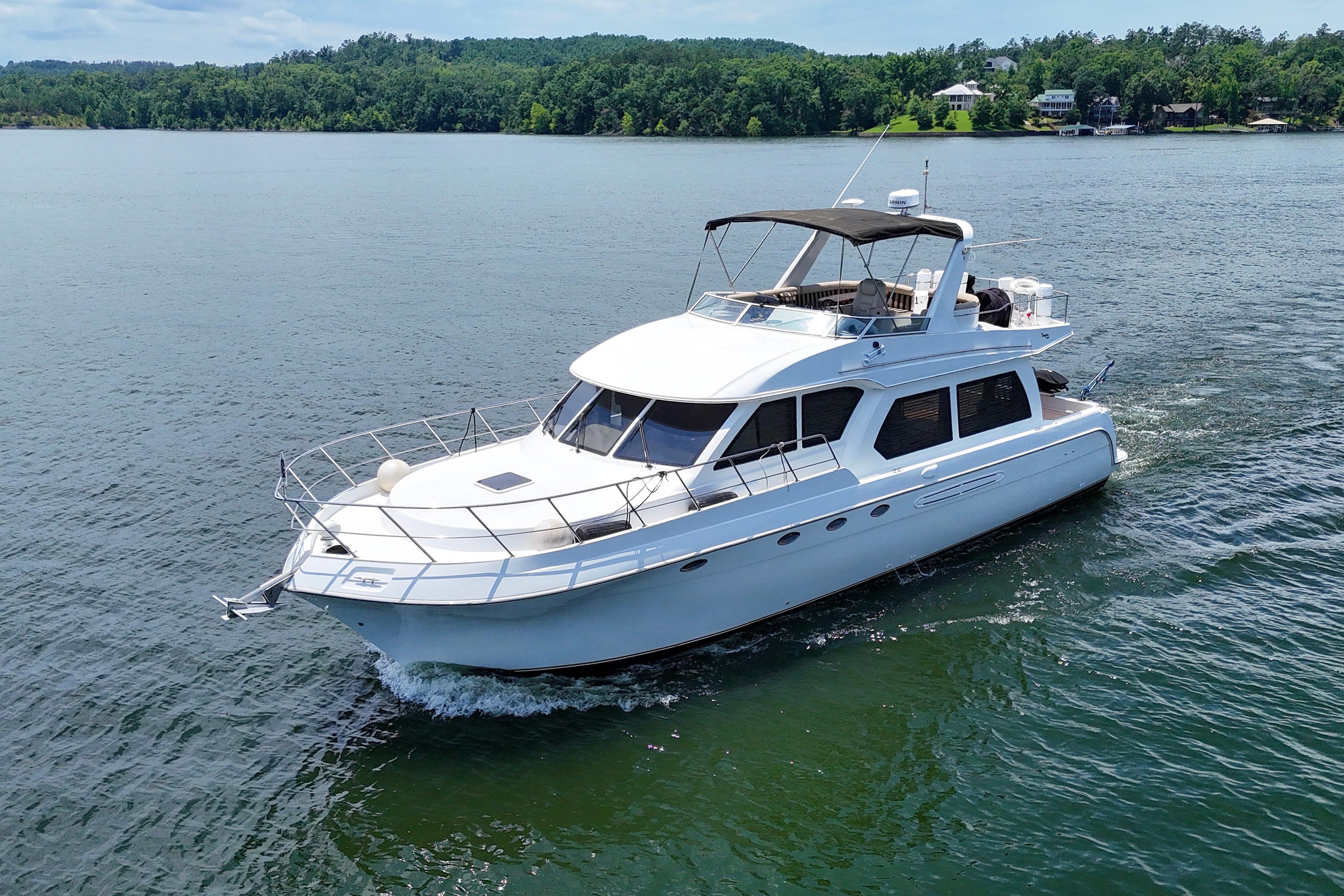Luxury 2007 Navigator 5100 yacht cruising on a serene lake with lush green shoreline.