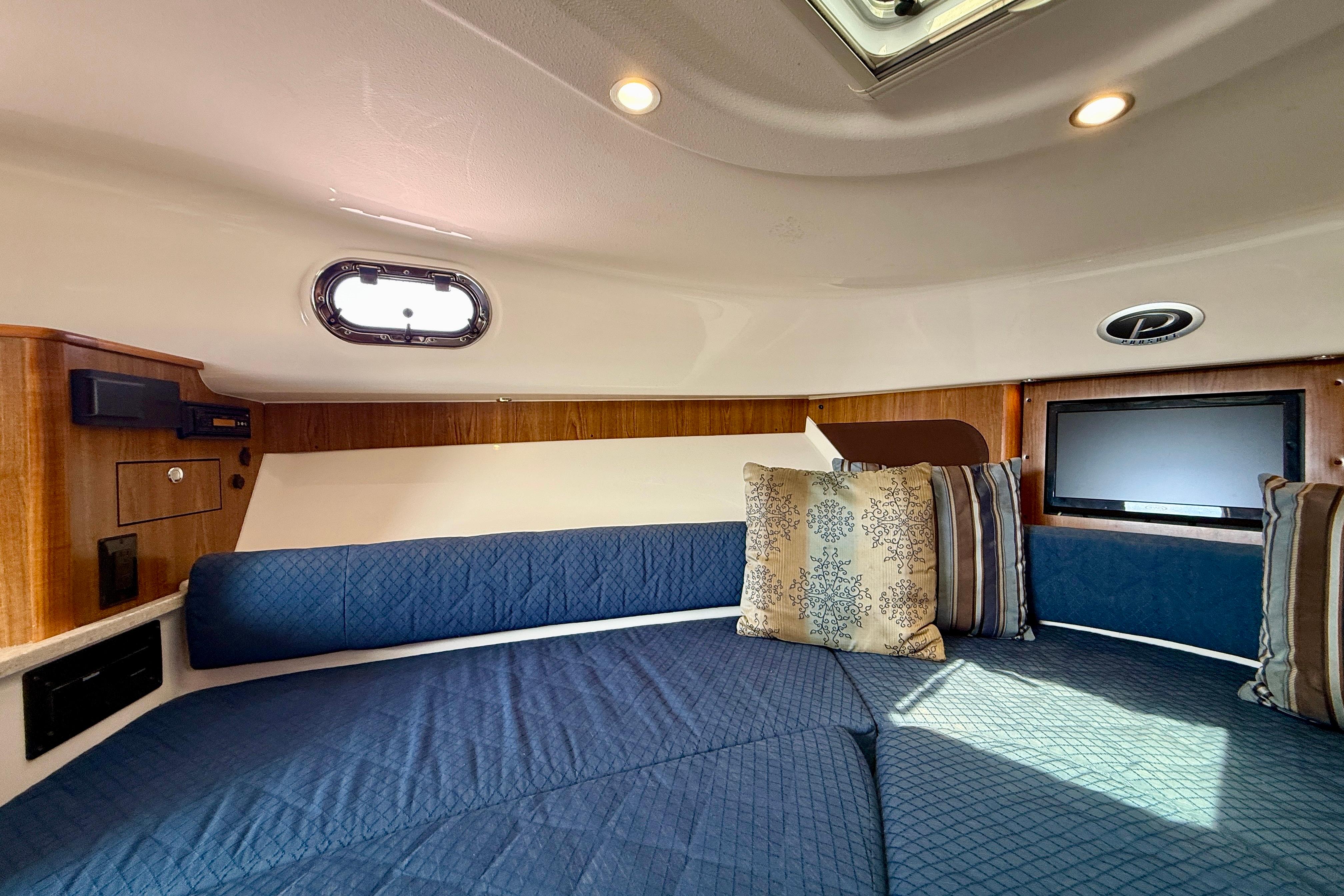 Interior cabin of 2012 Pursuit OS 345 Offshore with blue seating and decorative pillows.