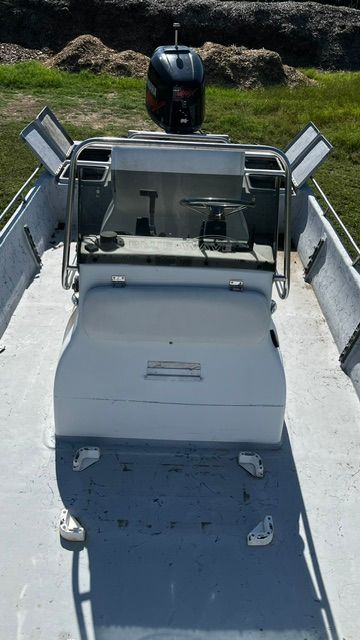 A boat with a console and outboard motor on dry land.